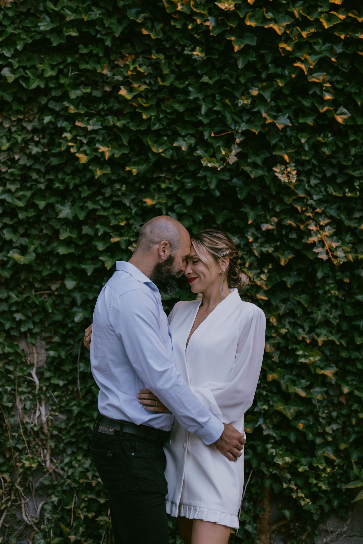 Romantic couple’s portrait in front of a lush ivy-covered wall