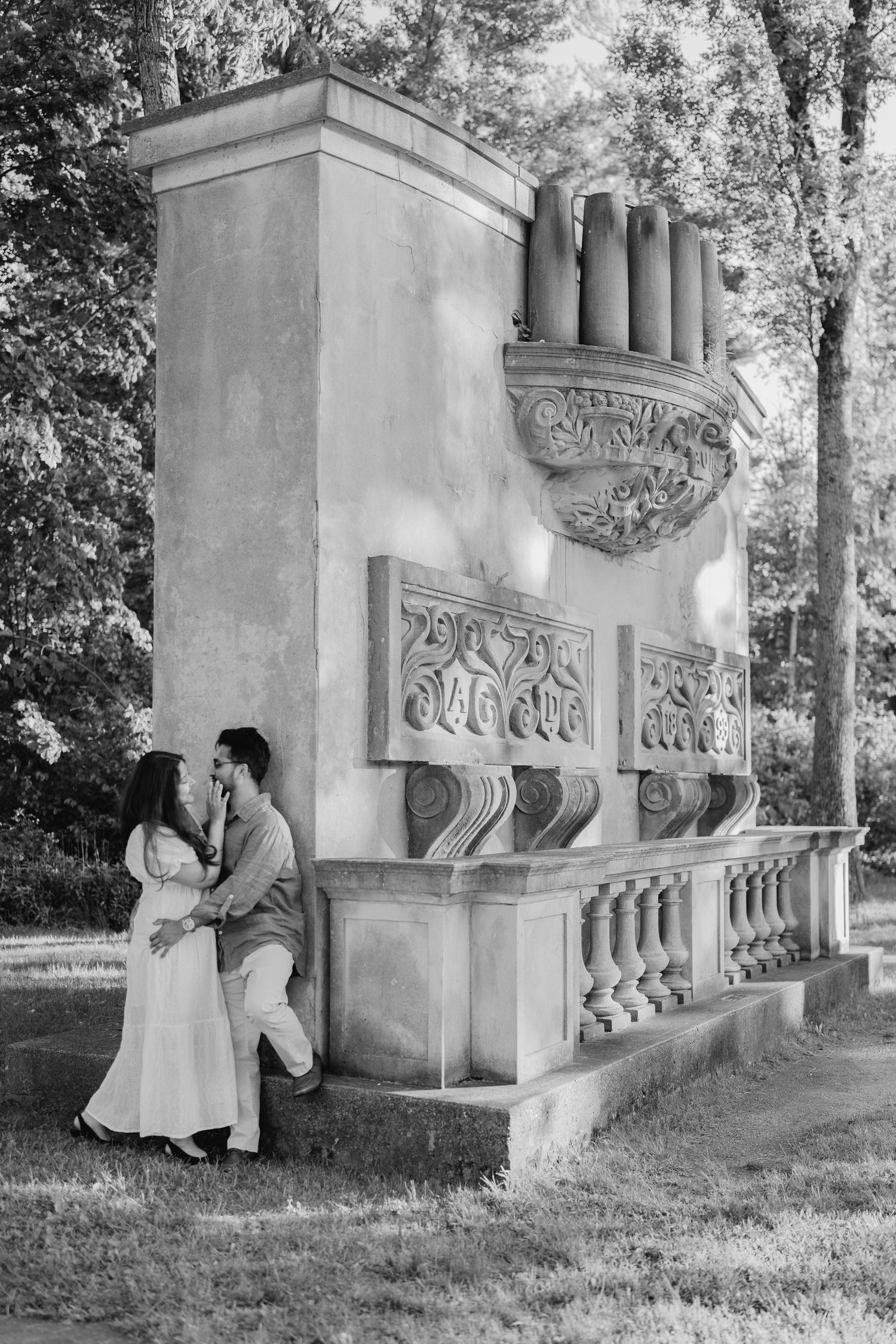 Romantic black and white engagement photo of couple leaning near sculptural monument