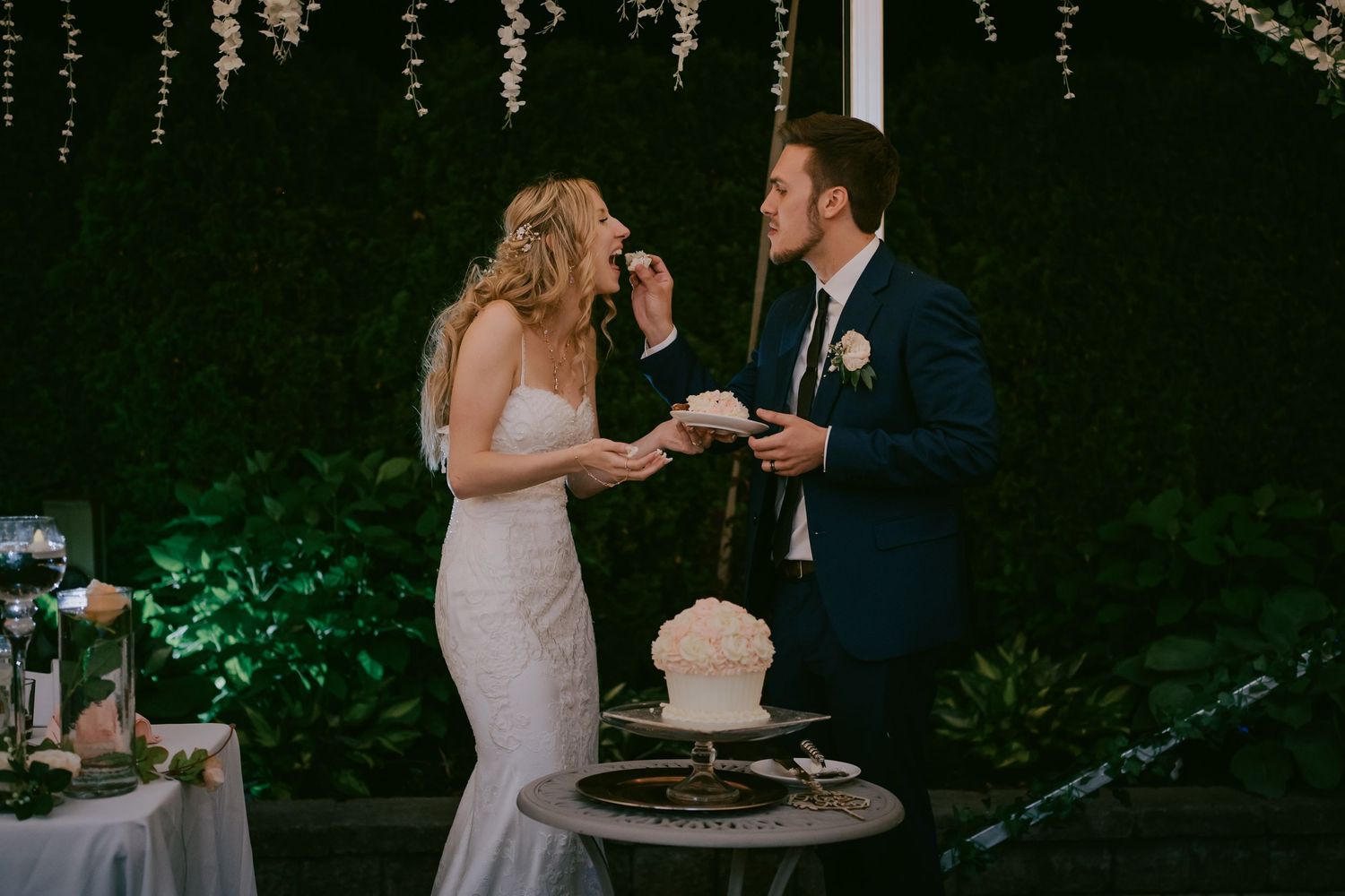 Bride feeding groom a piece of wedding cake at reception
