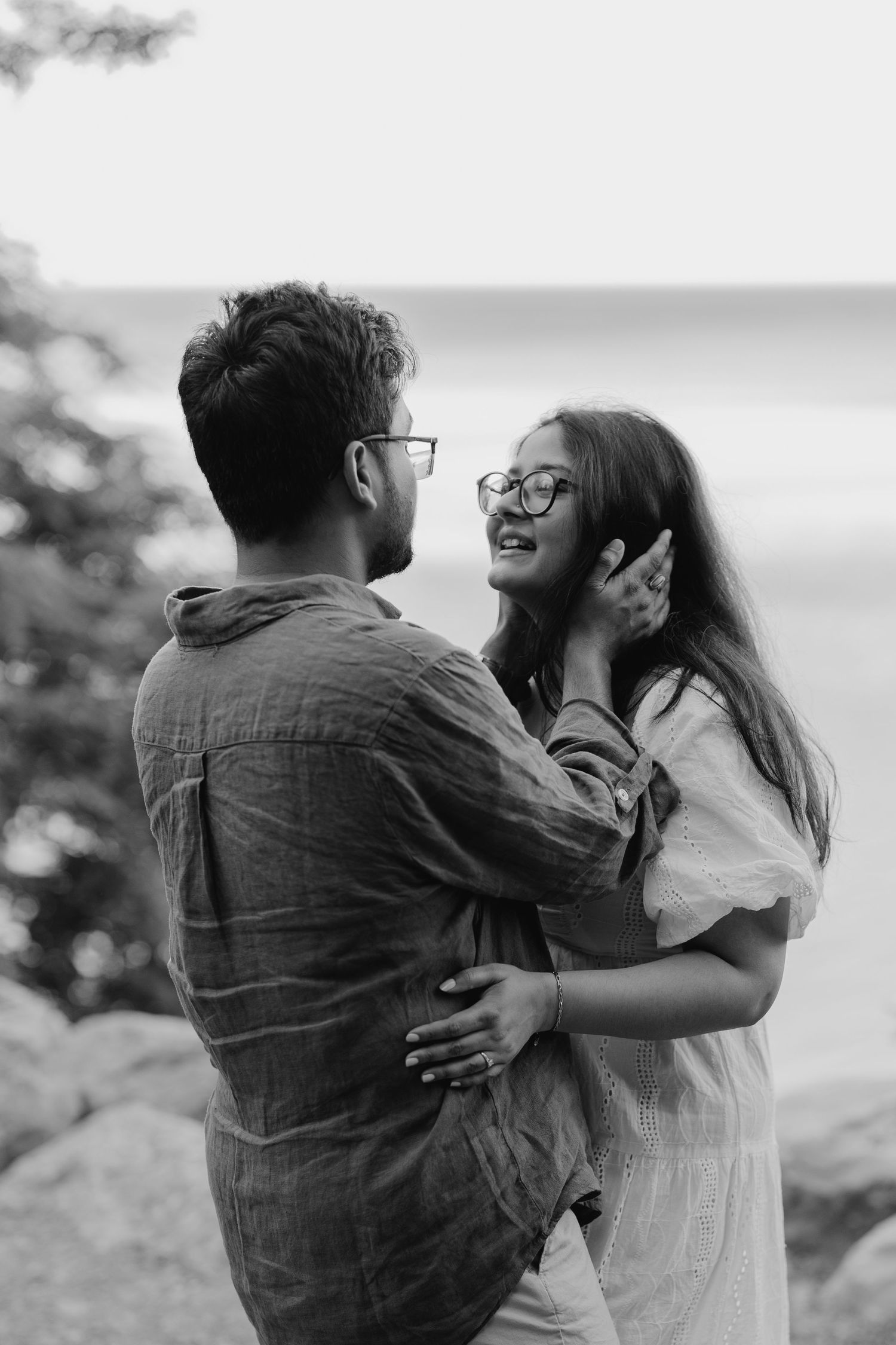 Joyful moment of couple laughing while holding hands near lakeside path