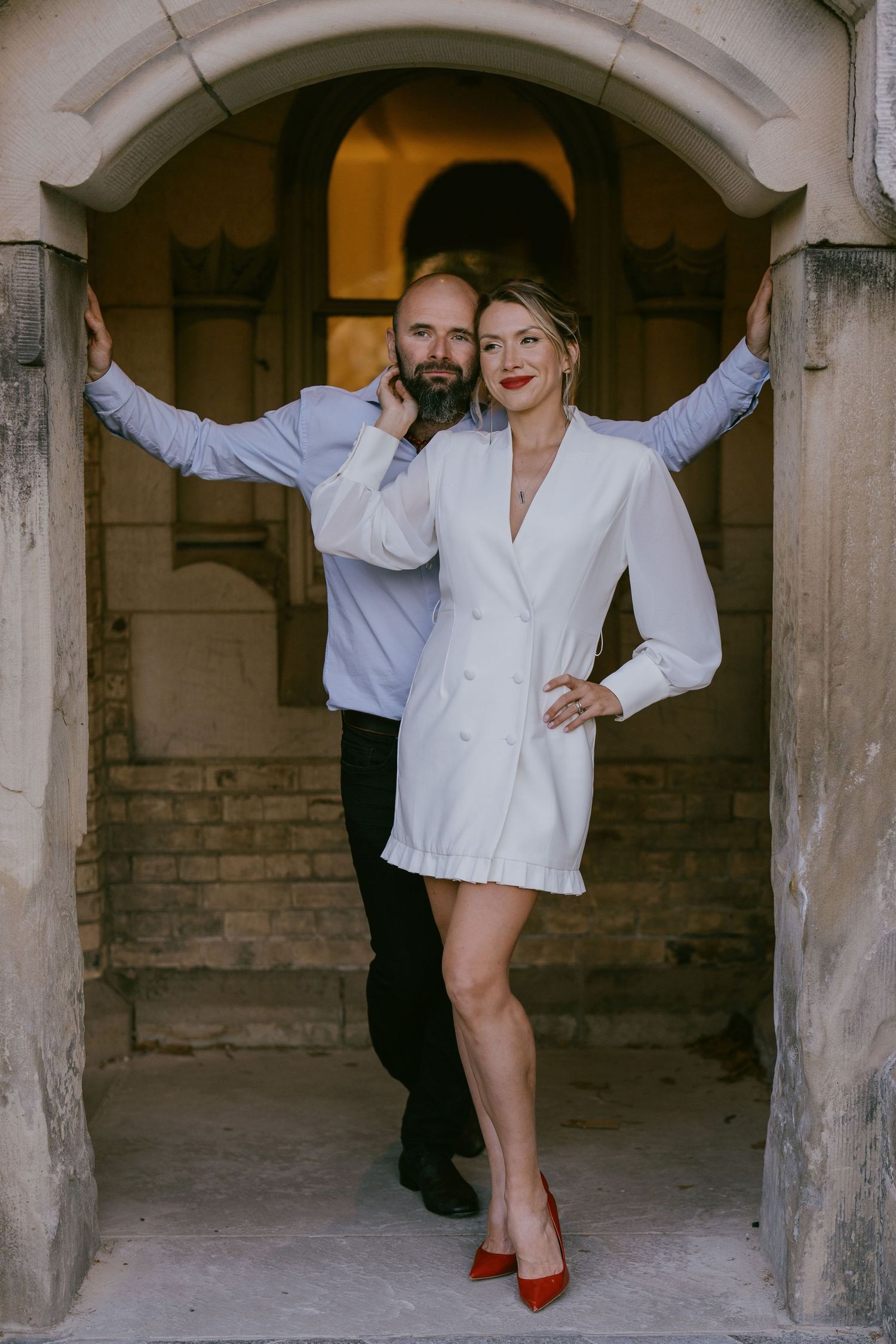 Couple laughing under historic archway during city engagement session