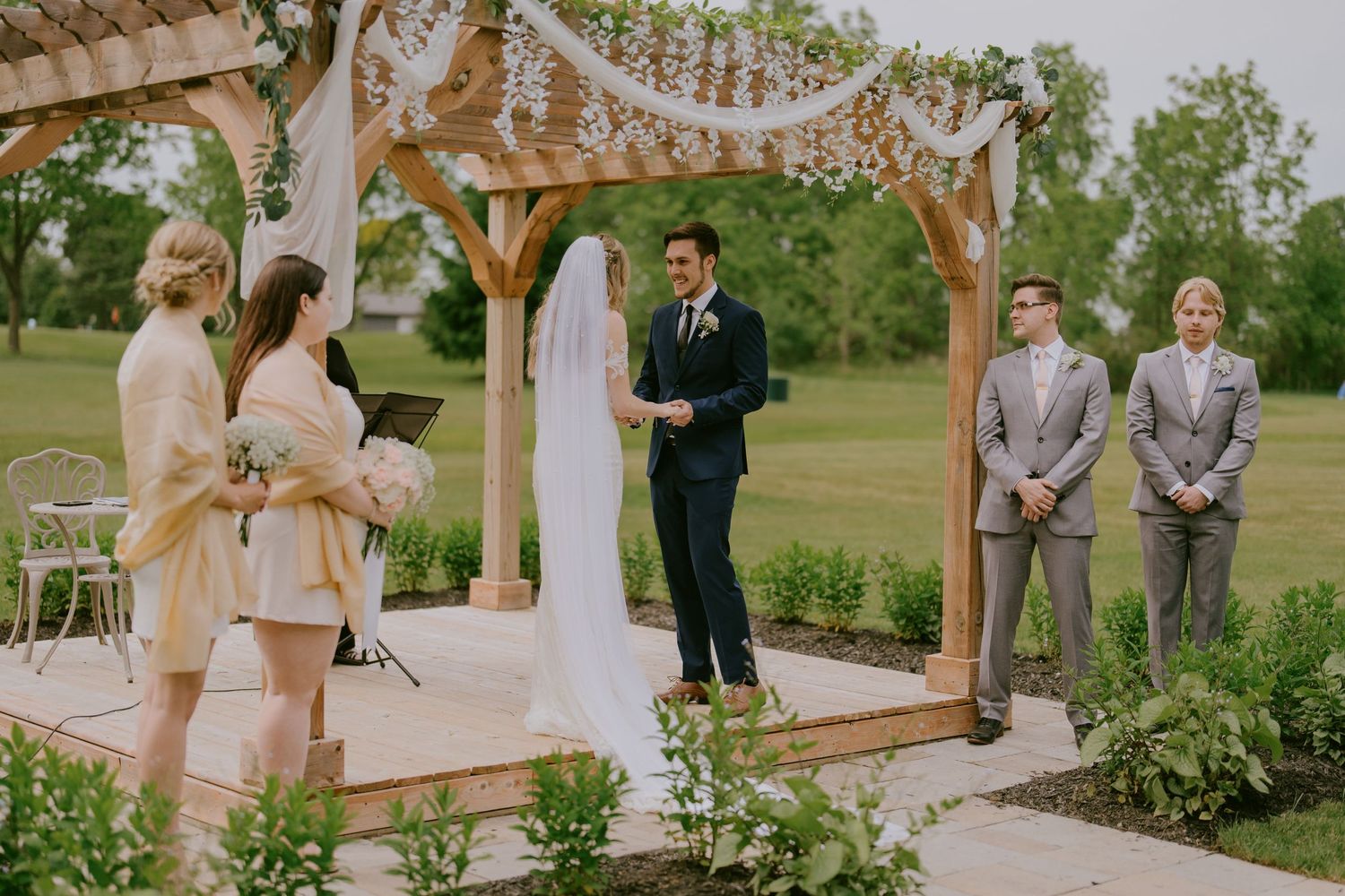 Bride and groom at altar with officiant and bridal party during ceremony