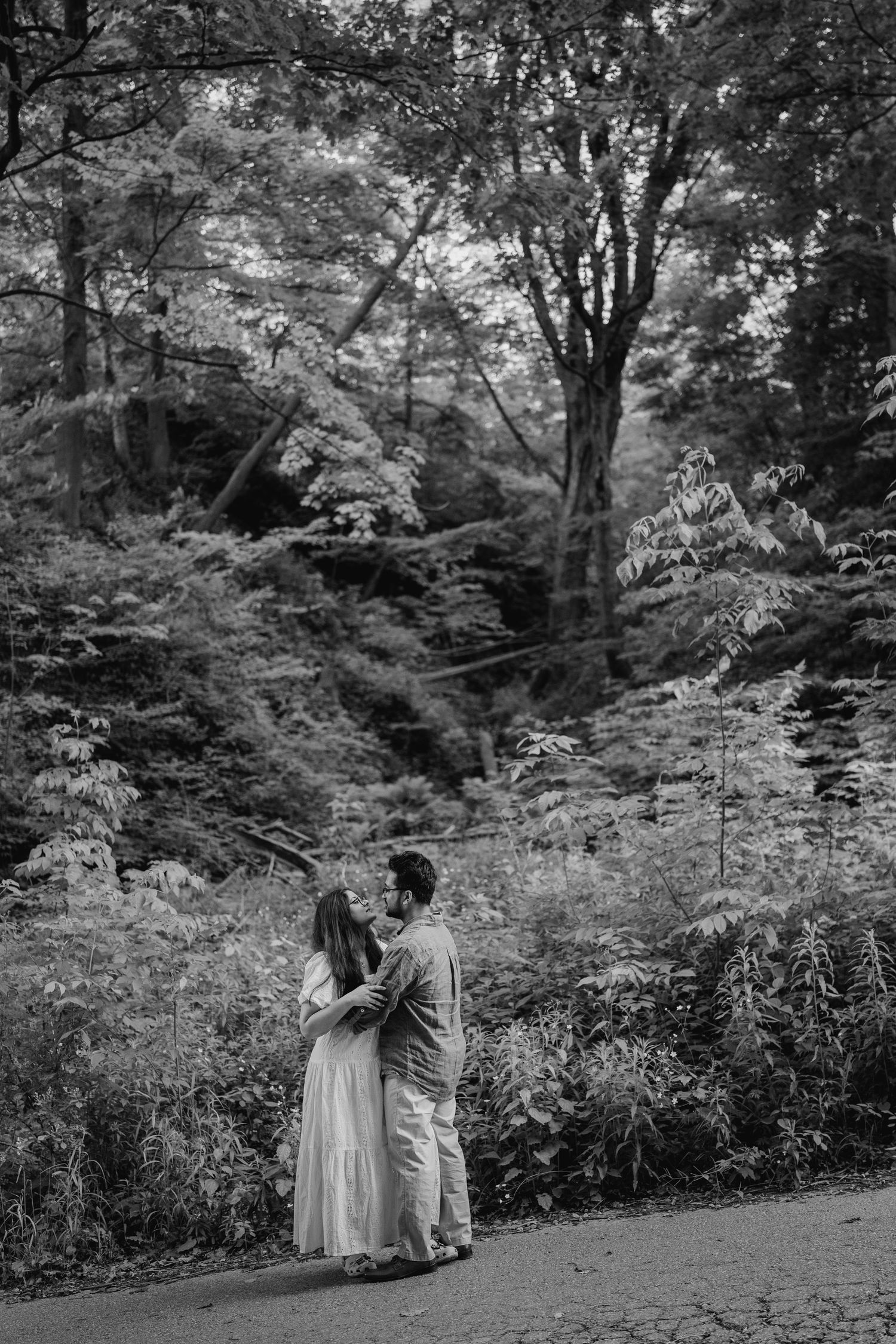 Black and white photo of couple standing quietly together in dense forest