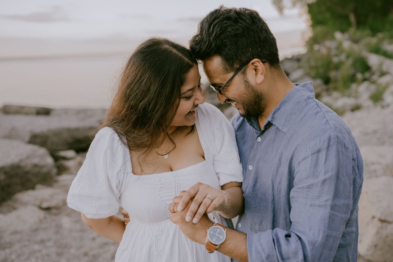 Engagement photo of couple holding hands by the water at sunset