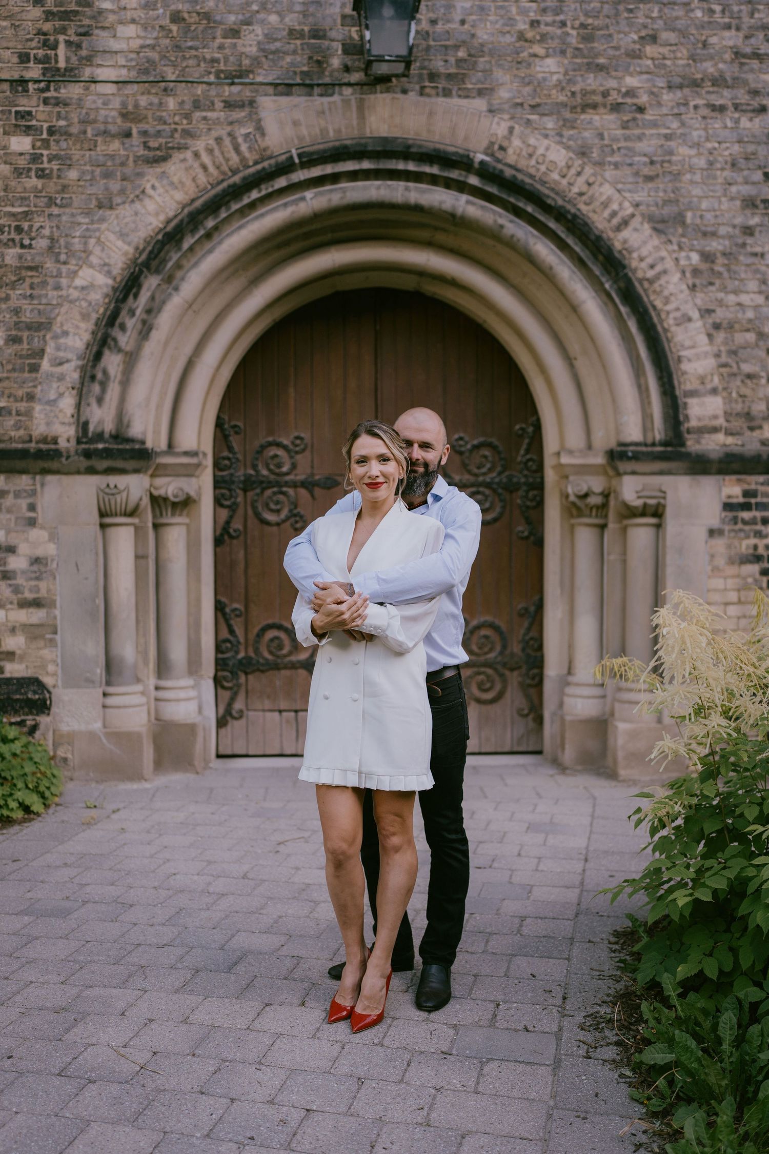 Romantic engagement photo of couple standing in front of stone arched doorway