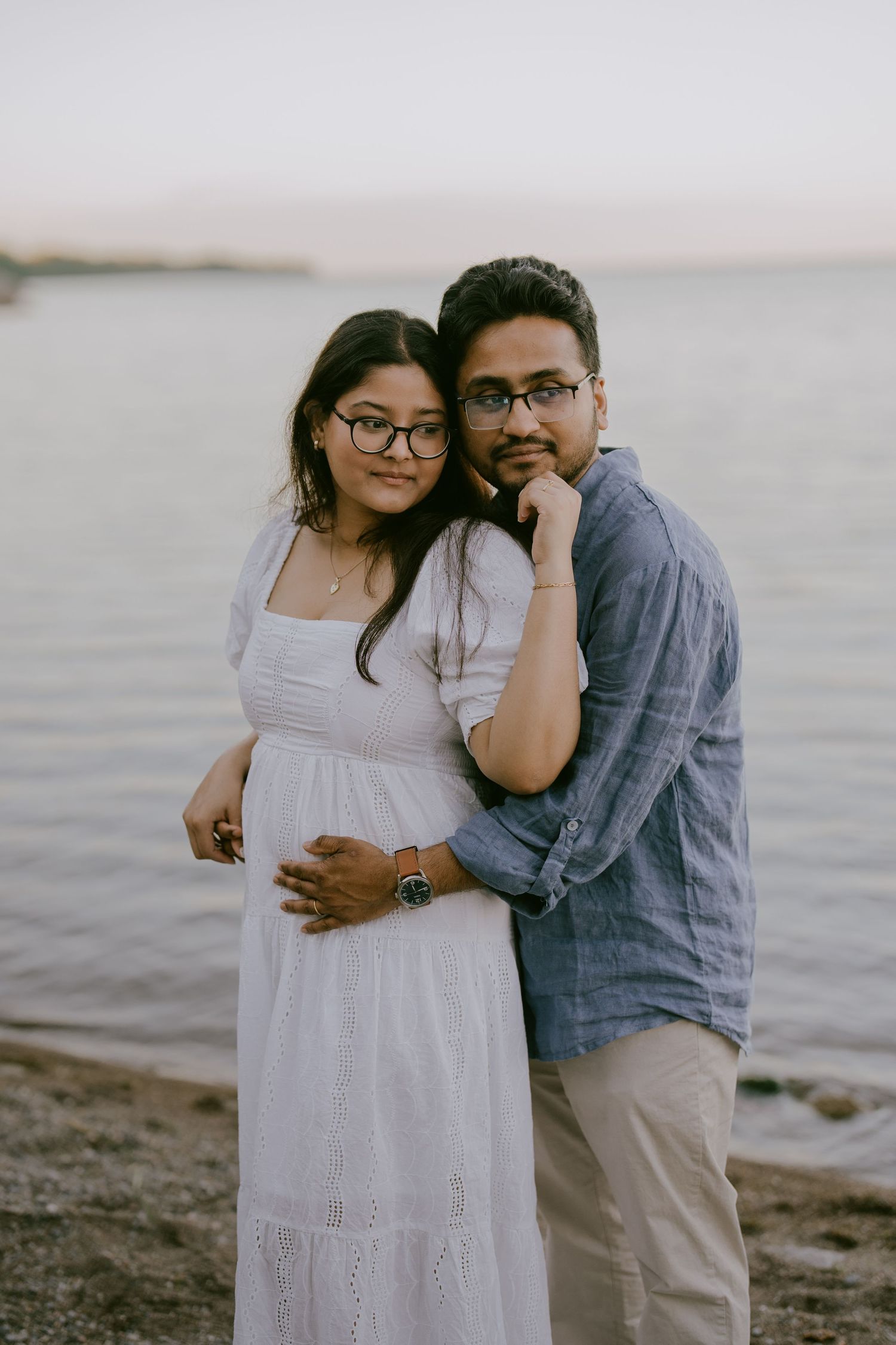 Engagement portrait of couple smiling while embracing at the lakeshore