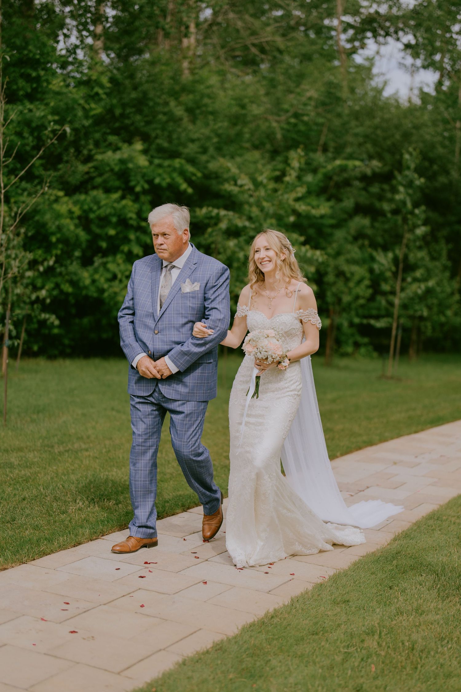 Bride walking down outdoor aisle arm-in-arm with father