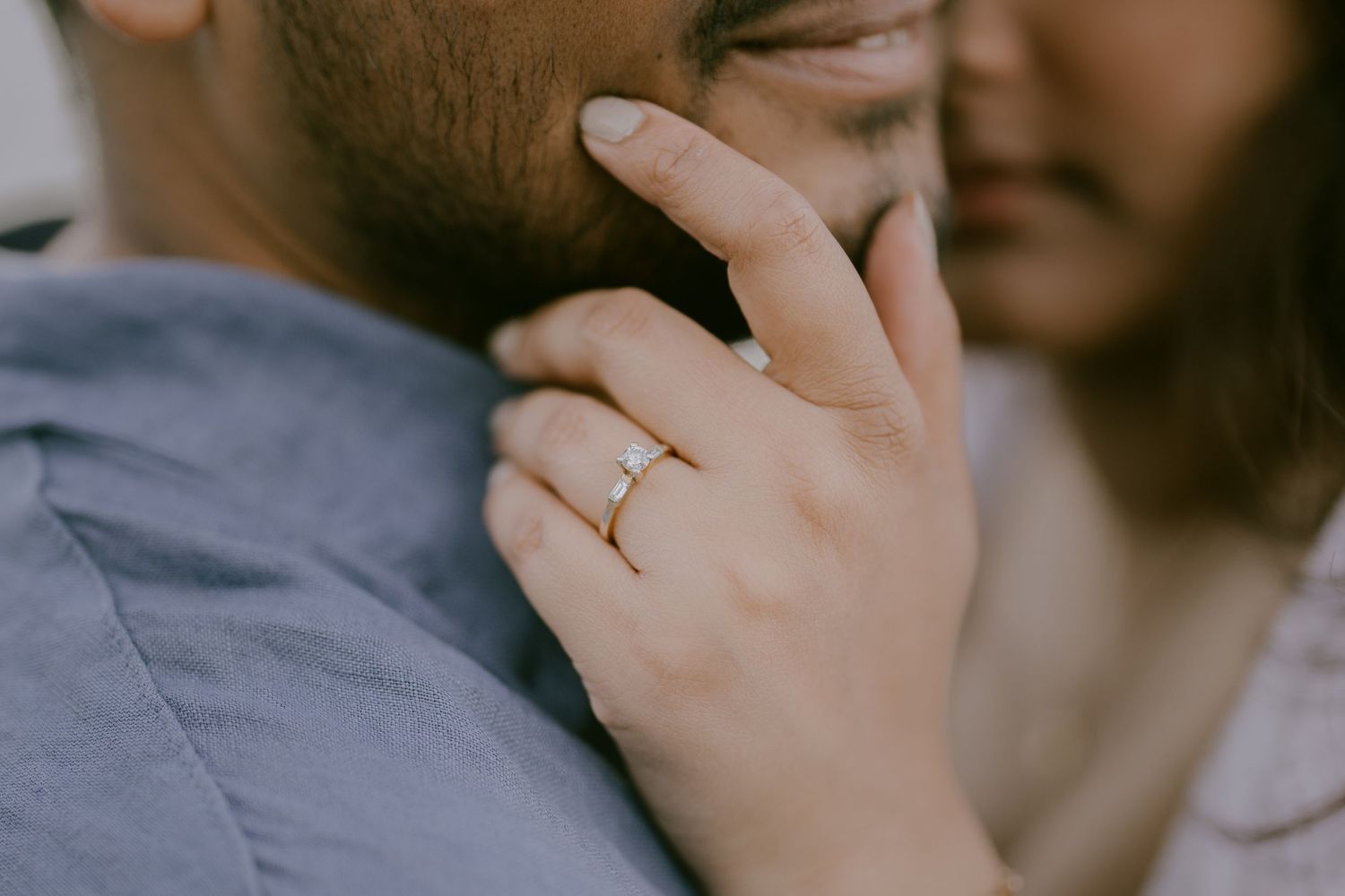 Close-up of engagement ring as woman gently holds partner’s shoulder