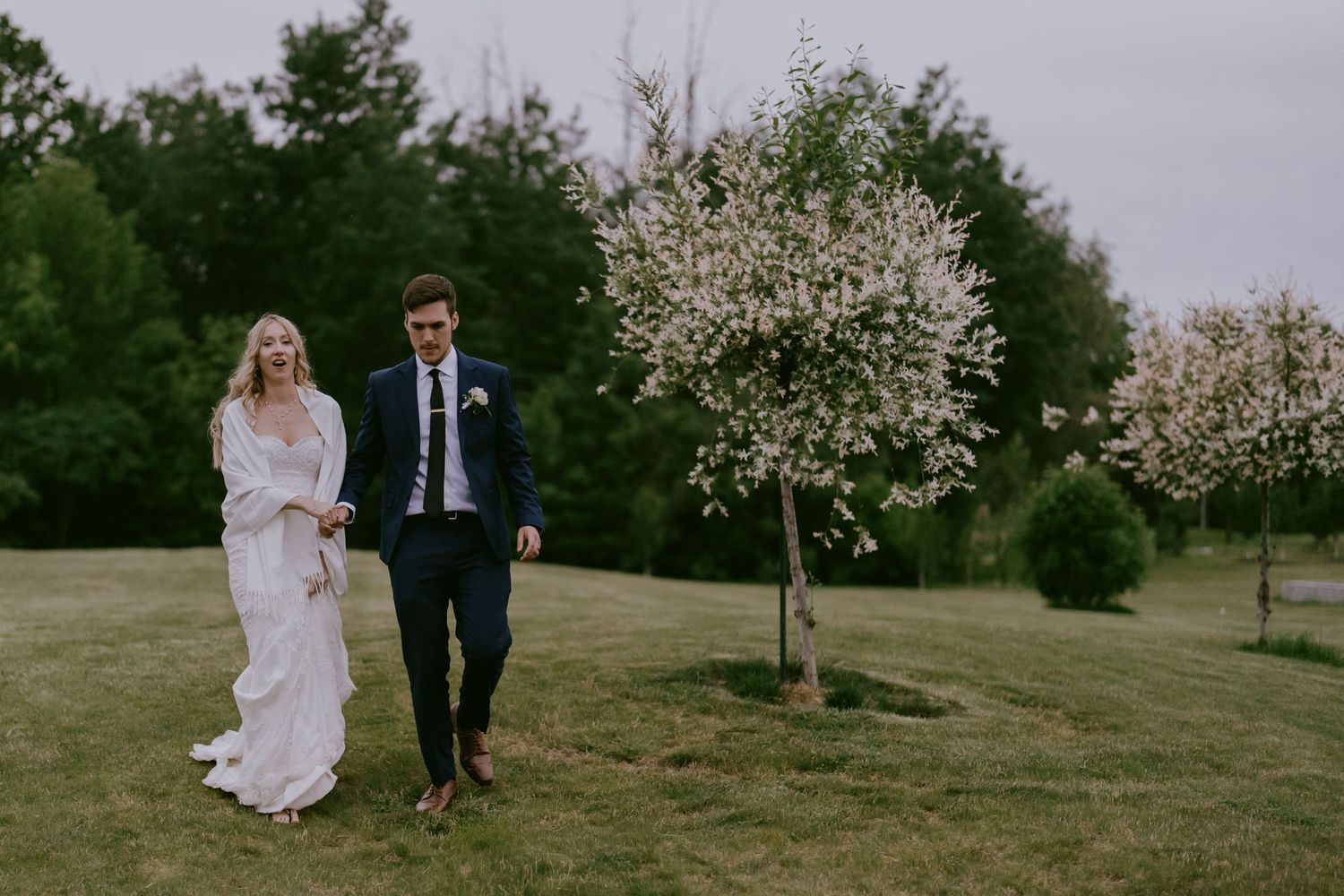 Bride and groom walking across green lawn after ceremony