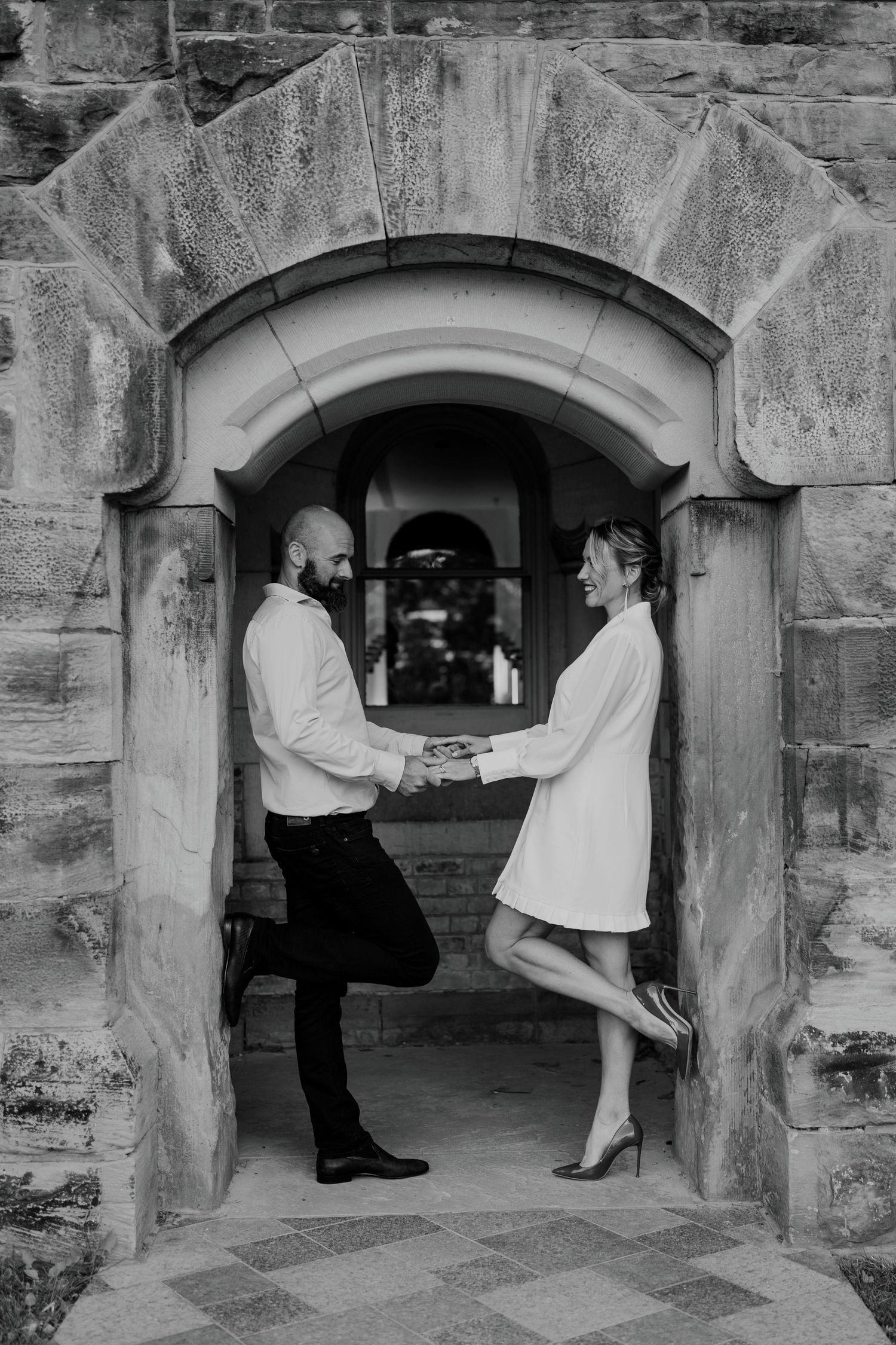 Creative engagement photo of couple framed in a gothic-style stone window