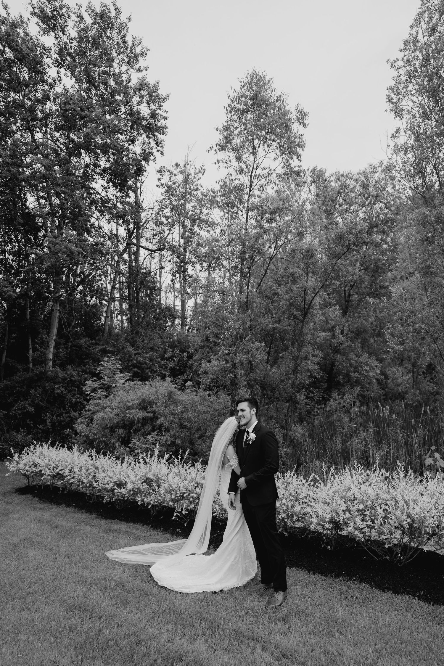 Black and white photo of newlyweds standing on garden lawn