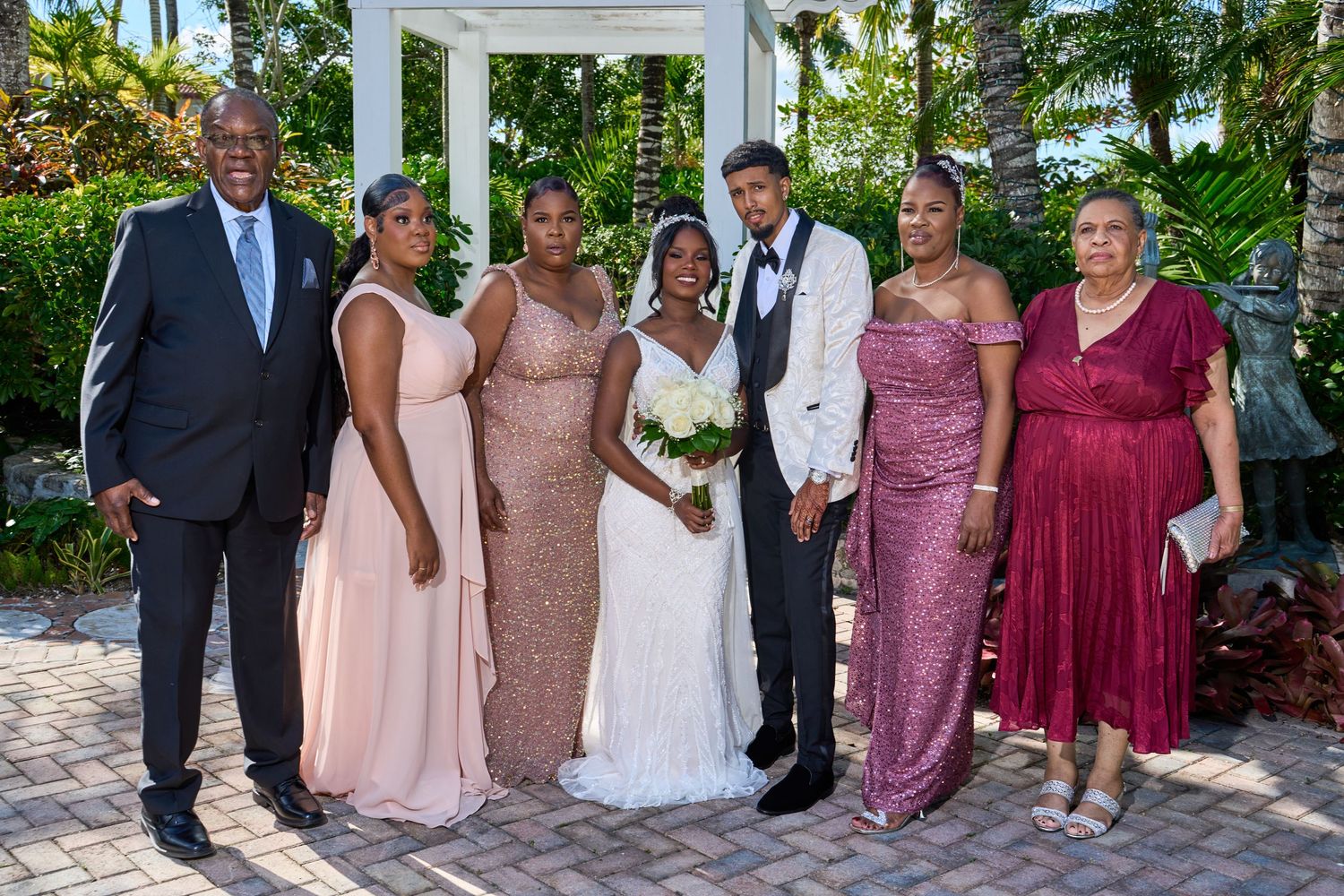 Wedding party group portrait with bride in white gown and guests in pink and burgundy attire.