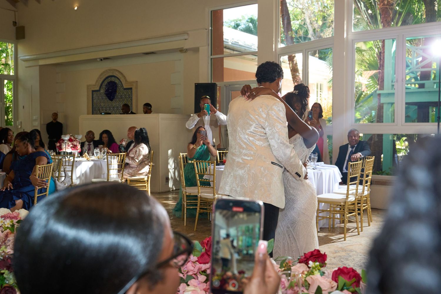 Bride and groom sharing first dance at elegant wedding reception with floral arrangements.