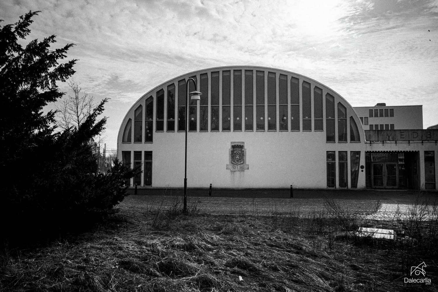 A black and white photograph of a curved barrel-vault style building with vertical lines and modern architectural design.