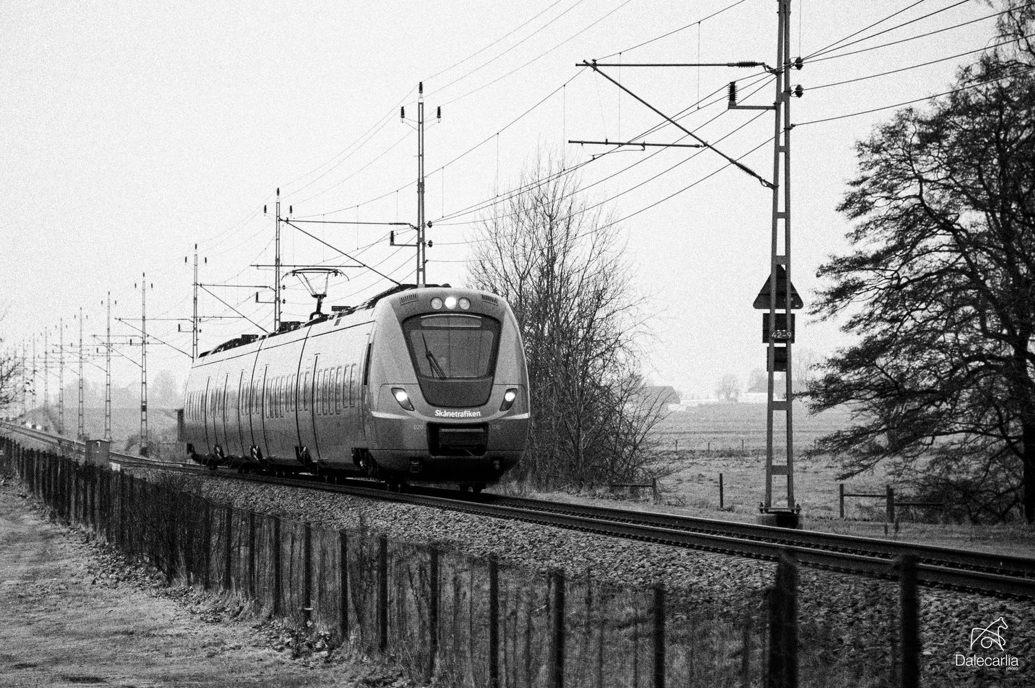 Black and white photograph showing a series of vintage railway scenes with trains and power lines stretching into the distance.