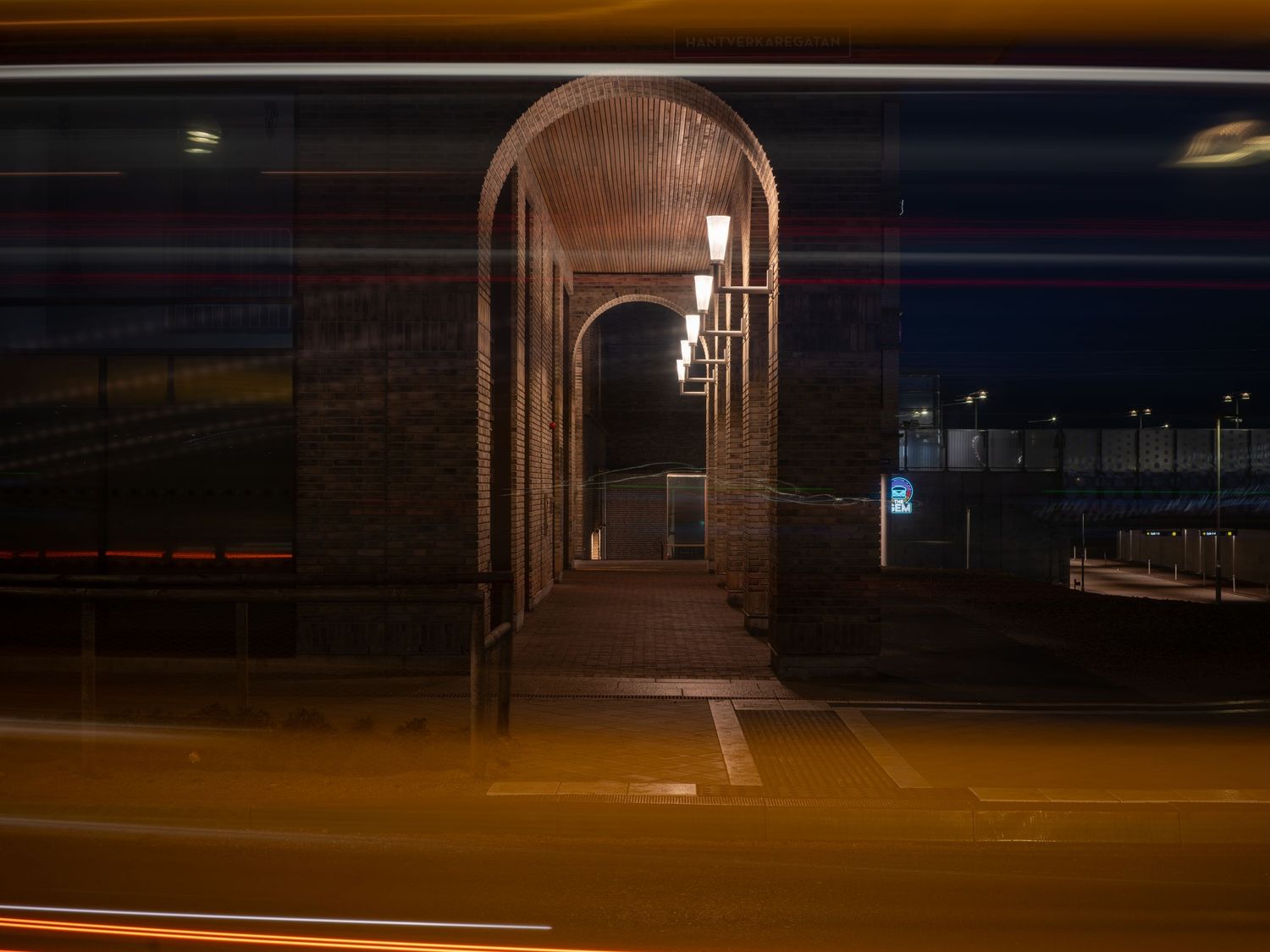 Dark nighttime view of a long empty corridor with fluorescent lighting illuminating the concrete walls and floor.