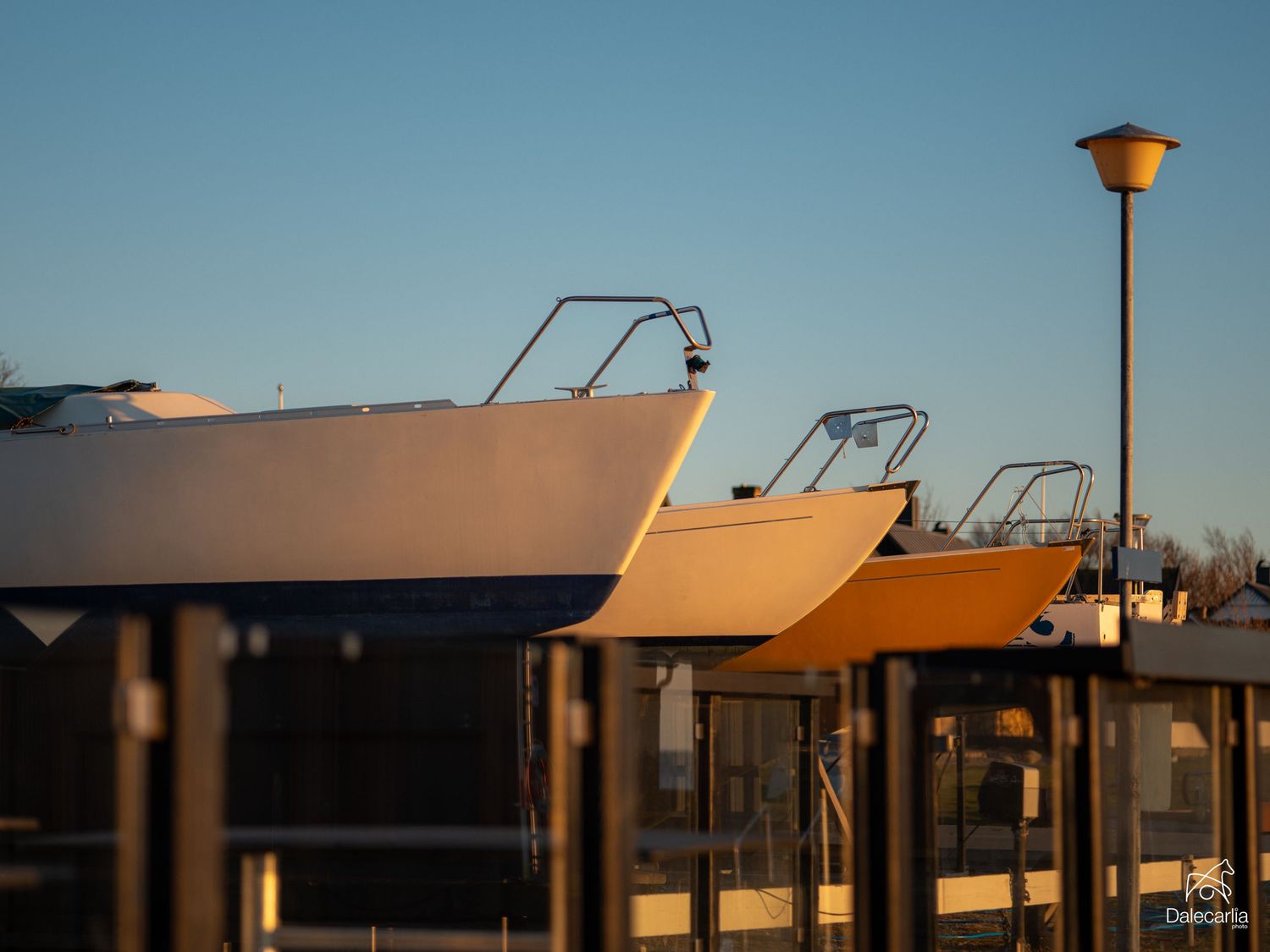 Two boats elevated on boat lifts at a marina during golden hour sunset with a street lamp in the background.