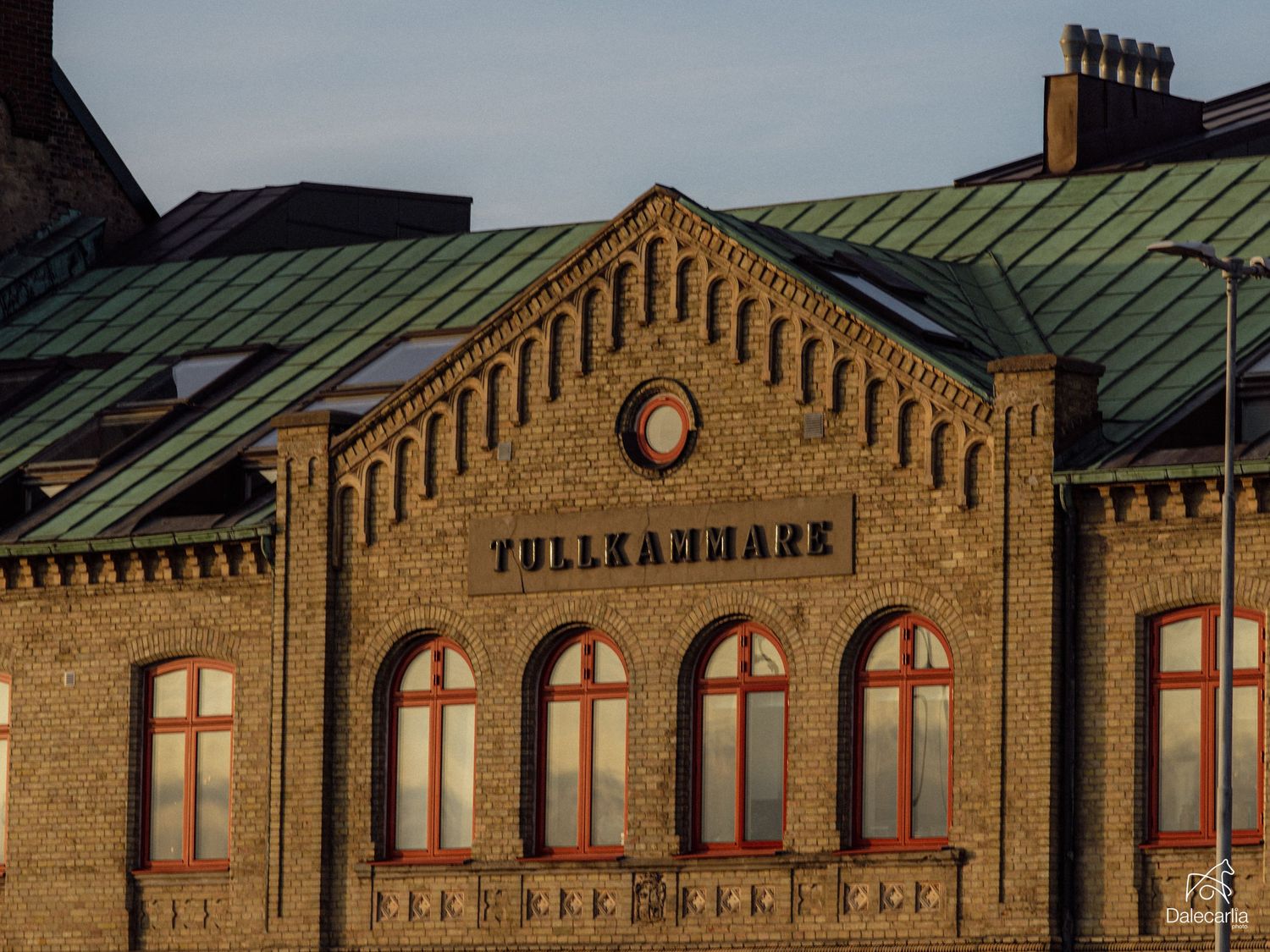 Historic Tullkammare brick building with green copper roof and arched windows in warm evening light.