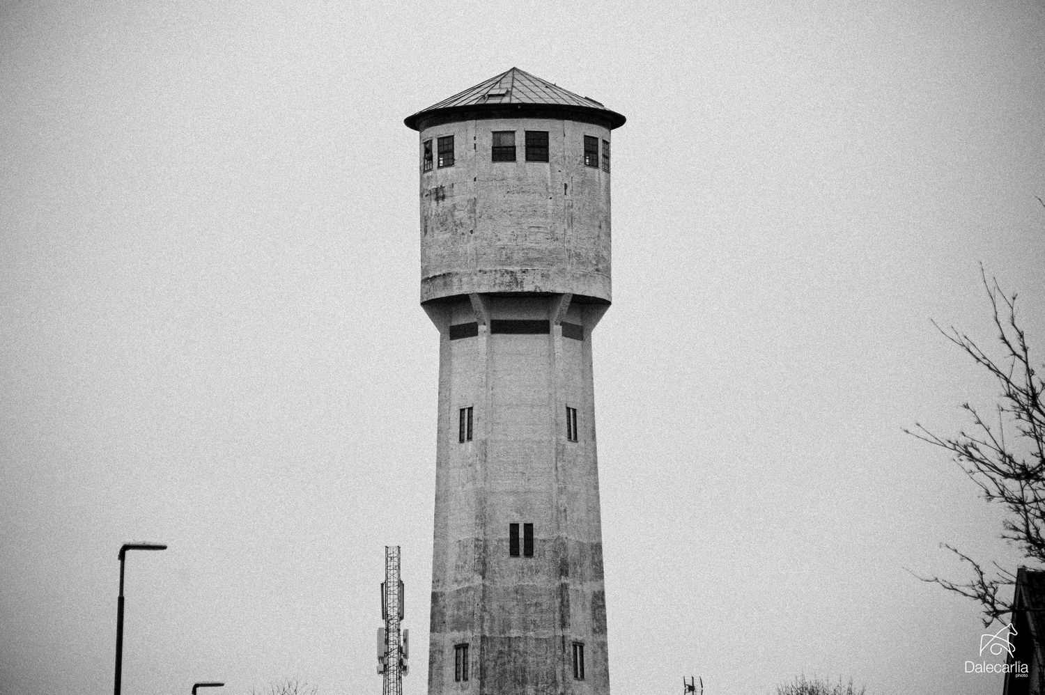 A collection of old concrete water towers photographed in black and white against a cloudy sky.