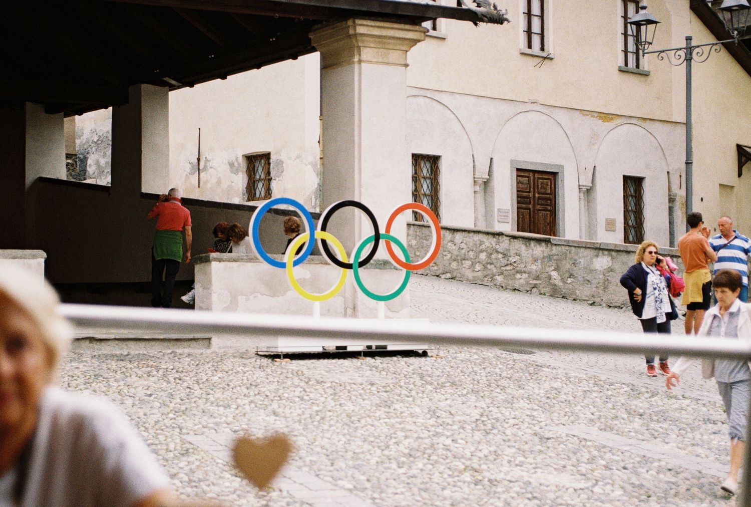 Olympic rings logo painted on white concrete wall in urban setting.