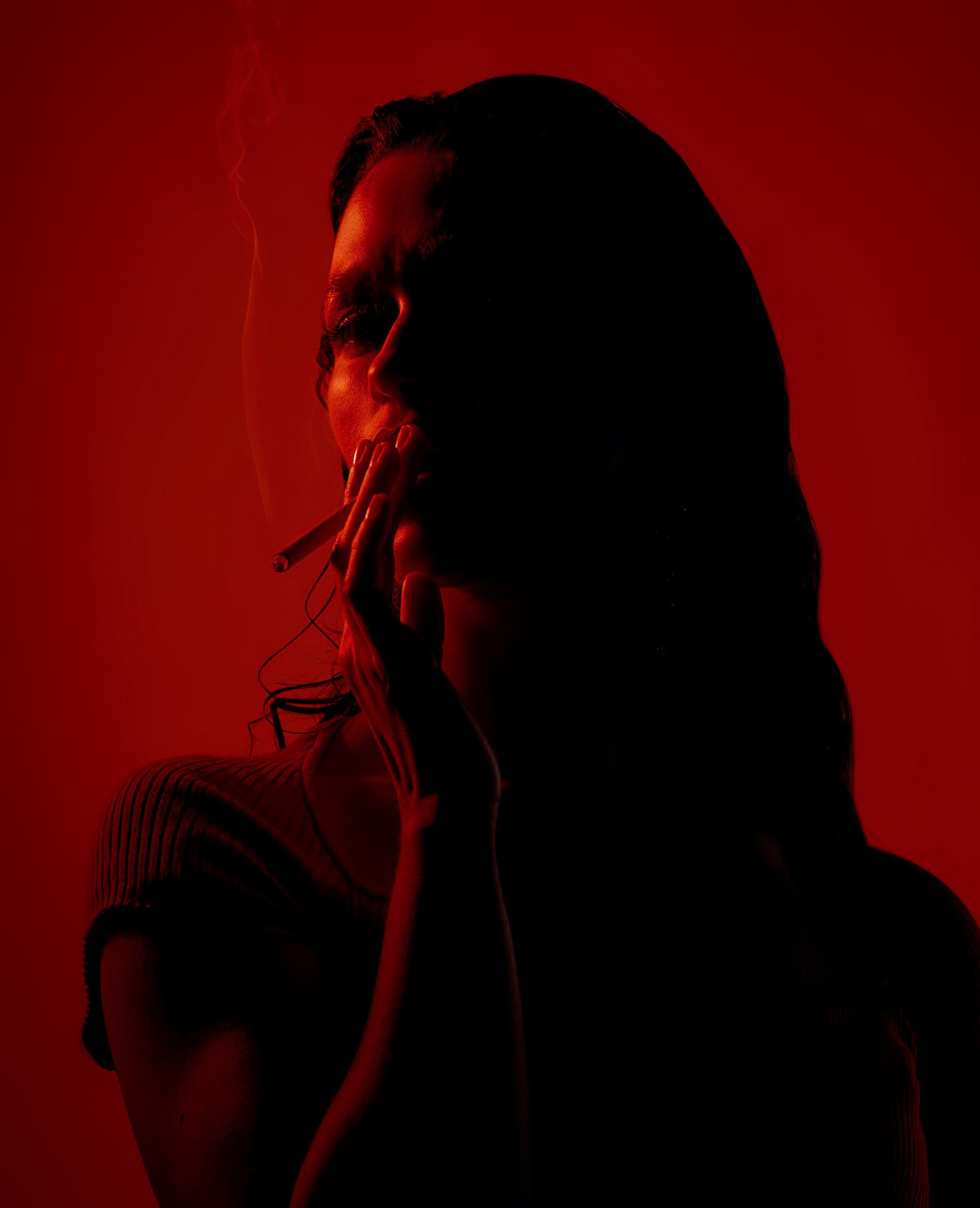 Moody red-tinted profile portrait with dramatic side lighting and long hair.
