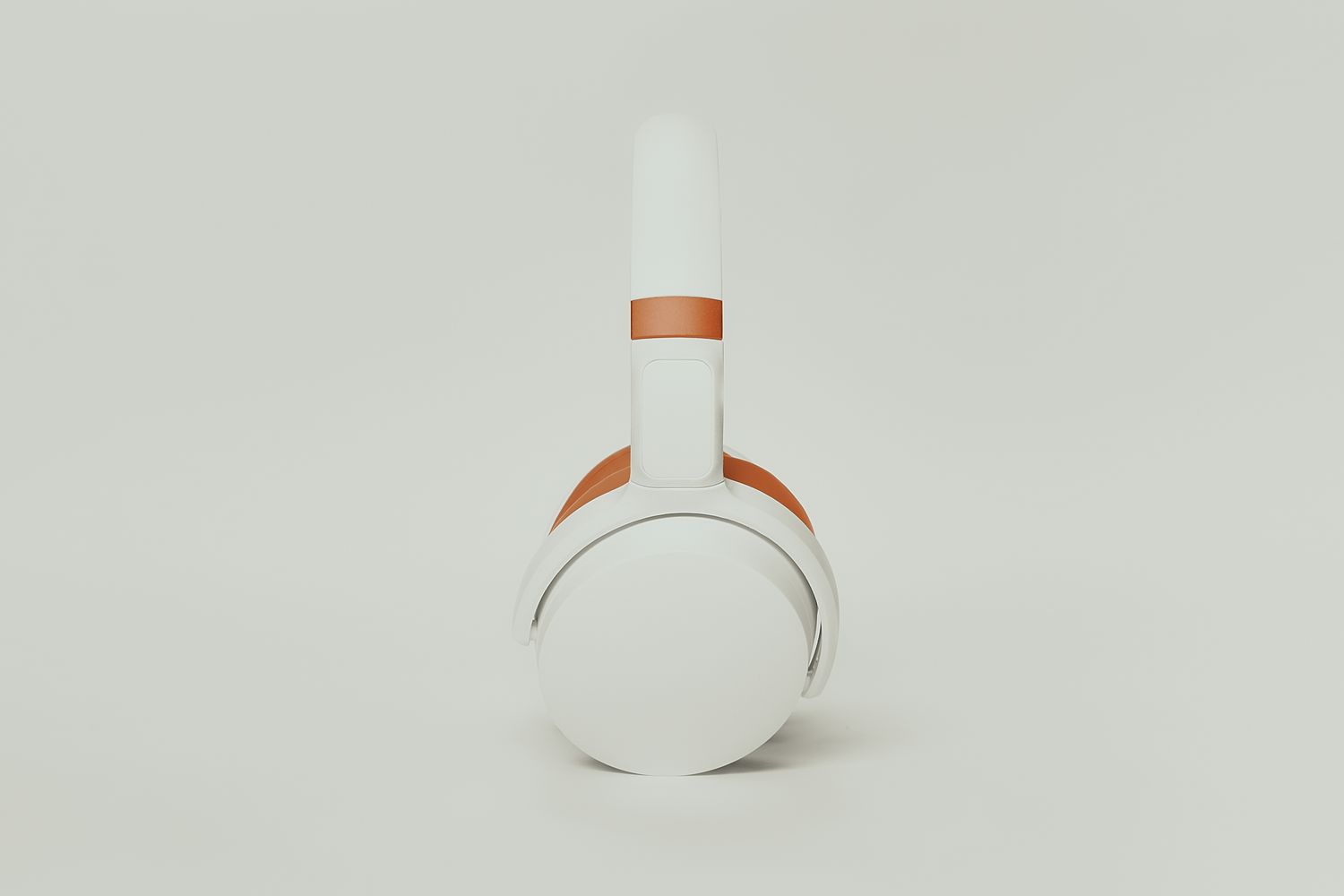 Professional product photography showing sleek white headphones with orange accents.