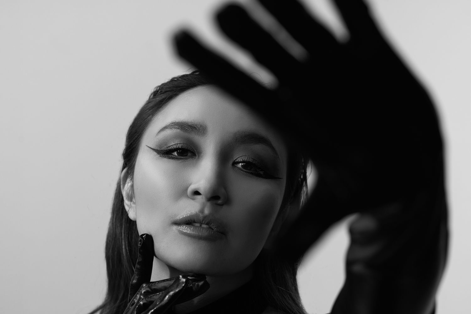 Black and white fashion portrait with dramatic hand shadow and long black gloves.
