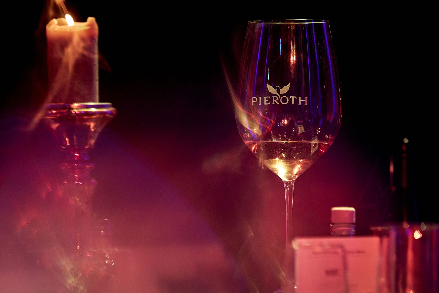 Elegant wine glasses with candlelight creating a romantic atmosphere against dark background.