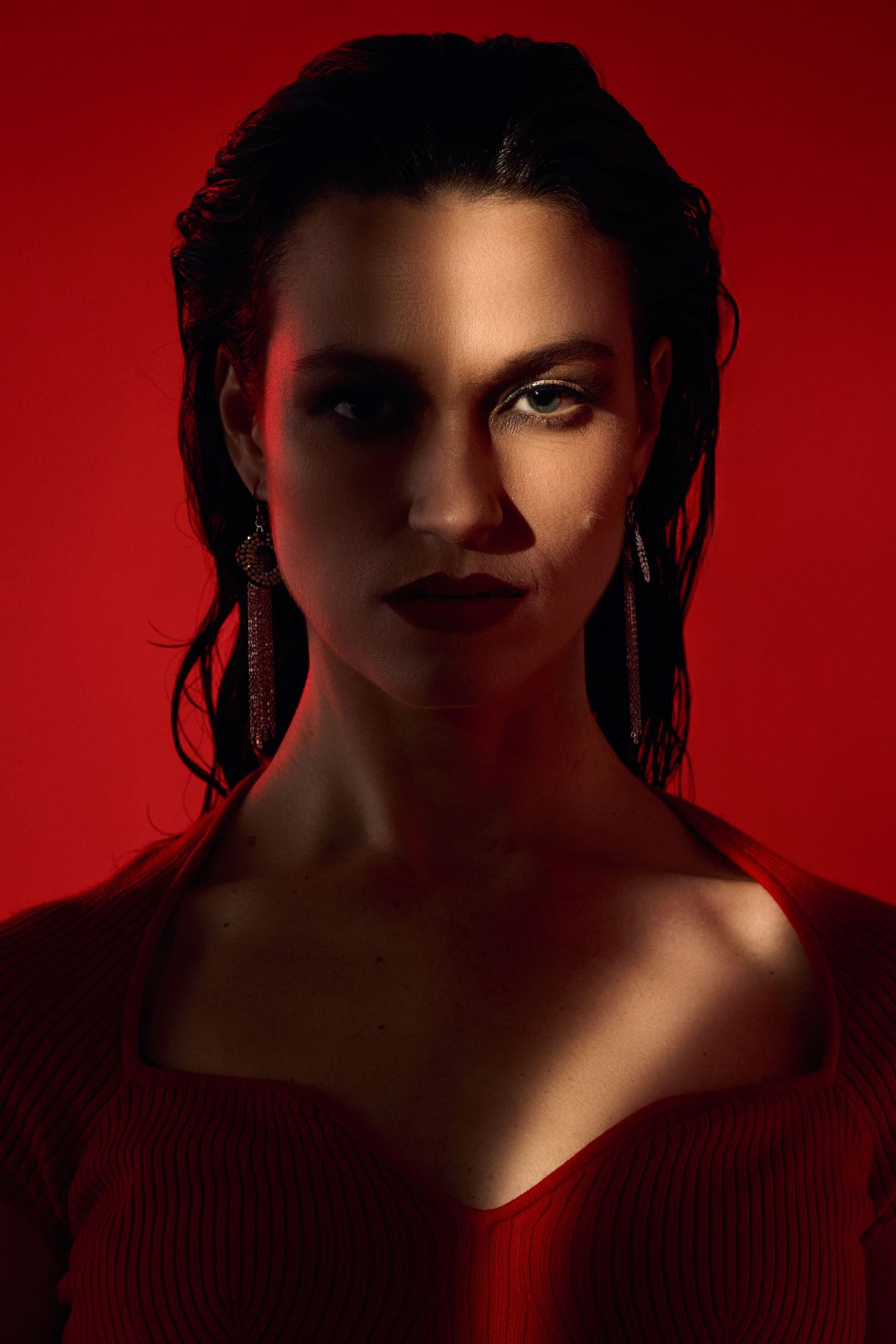 Dramatic portrait with red lighting showing intense gaze and wet-look hair.