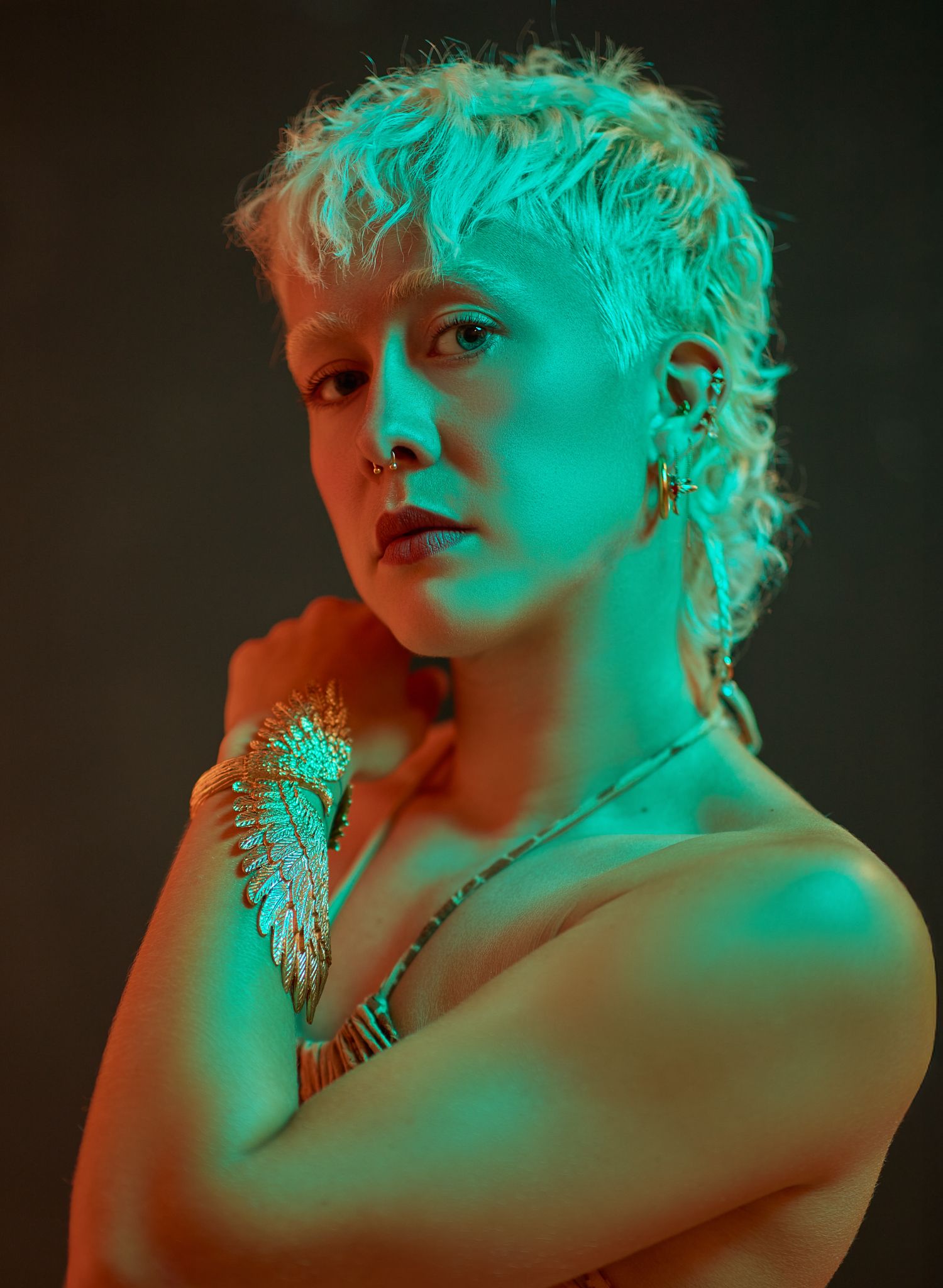 Artistic portrait with dramatic turquoise and orange lighting creating a moody atmosphere.