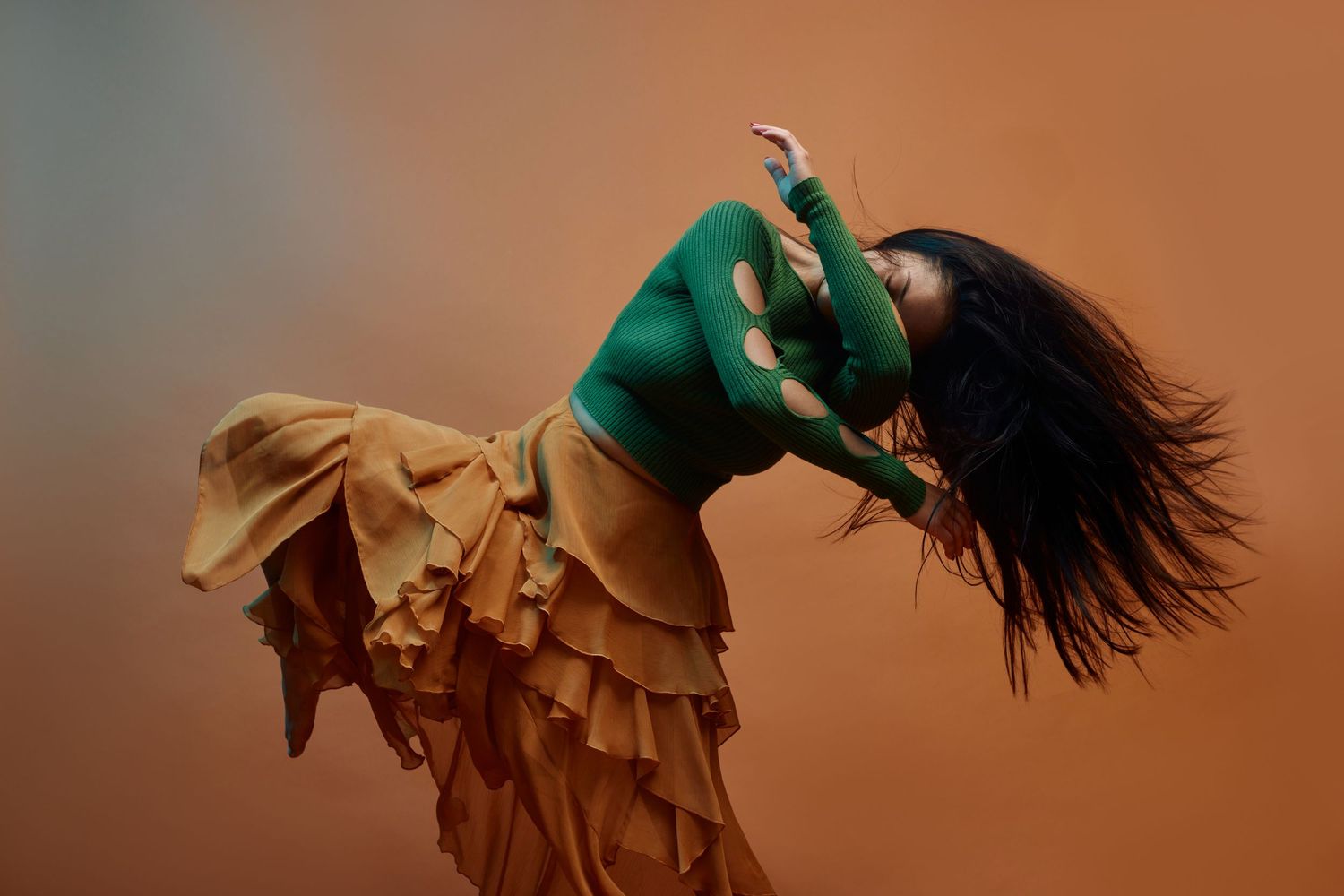 A ballet dancer in a flowing white dress performs an elegant leap against a warm orange-tinted background.