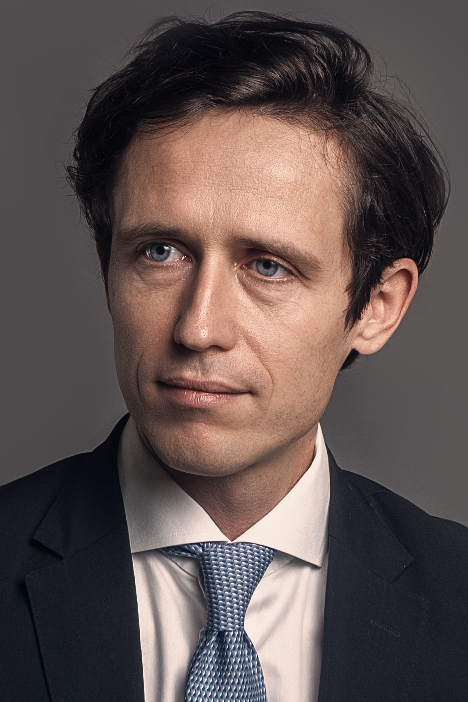 Close-up portrait series in business attire against grey studio backdrop.