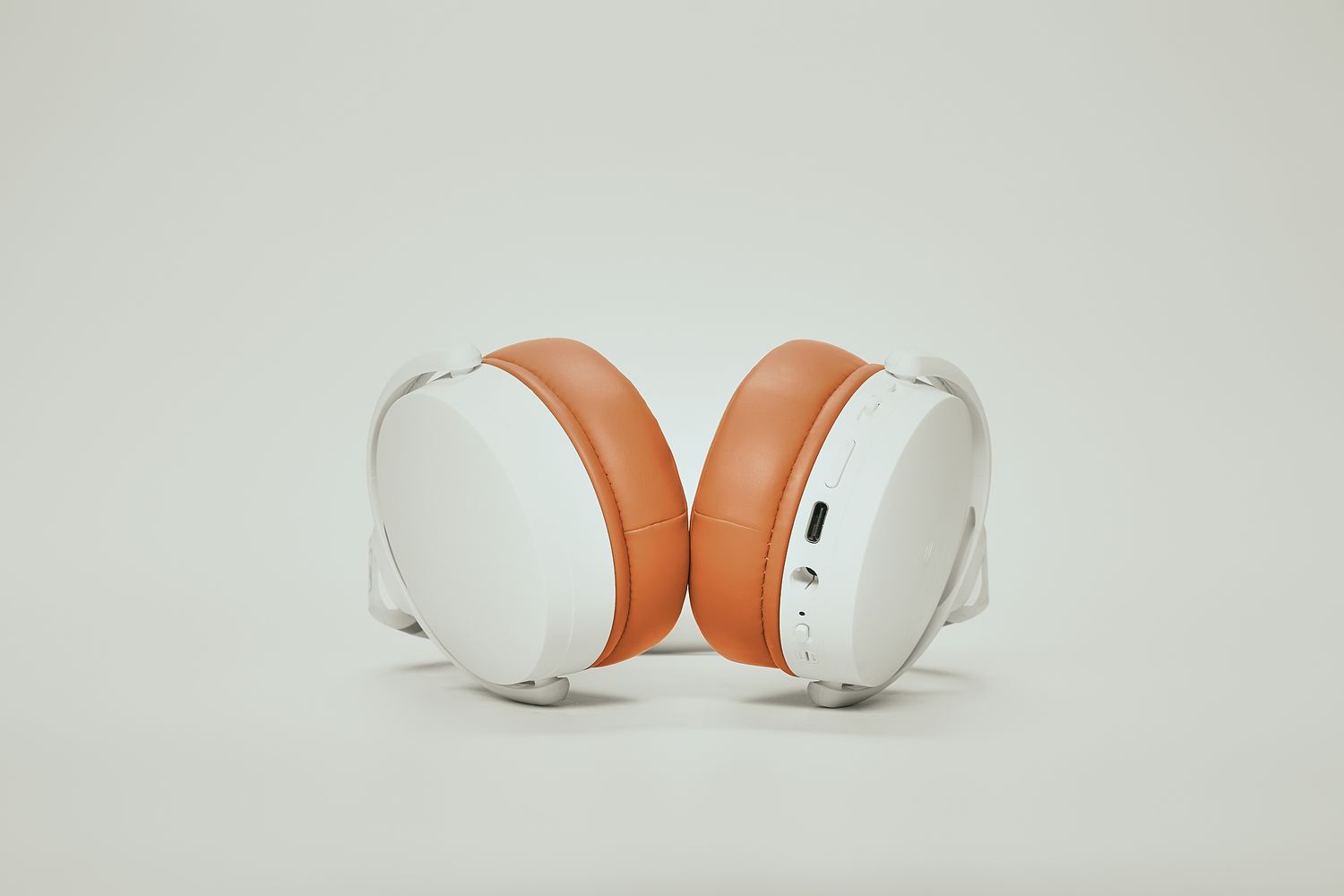 Clean studio shots of modern white and orange wireless headphones from different perspectives.