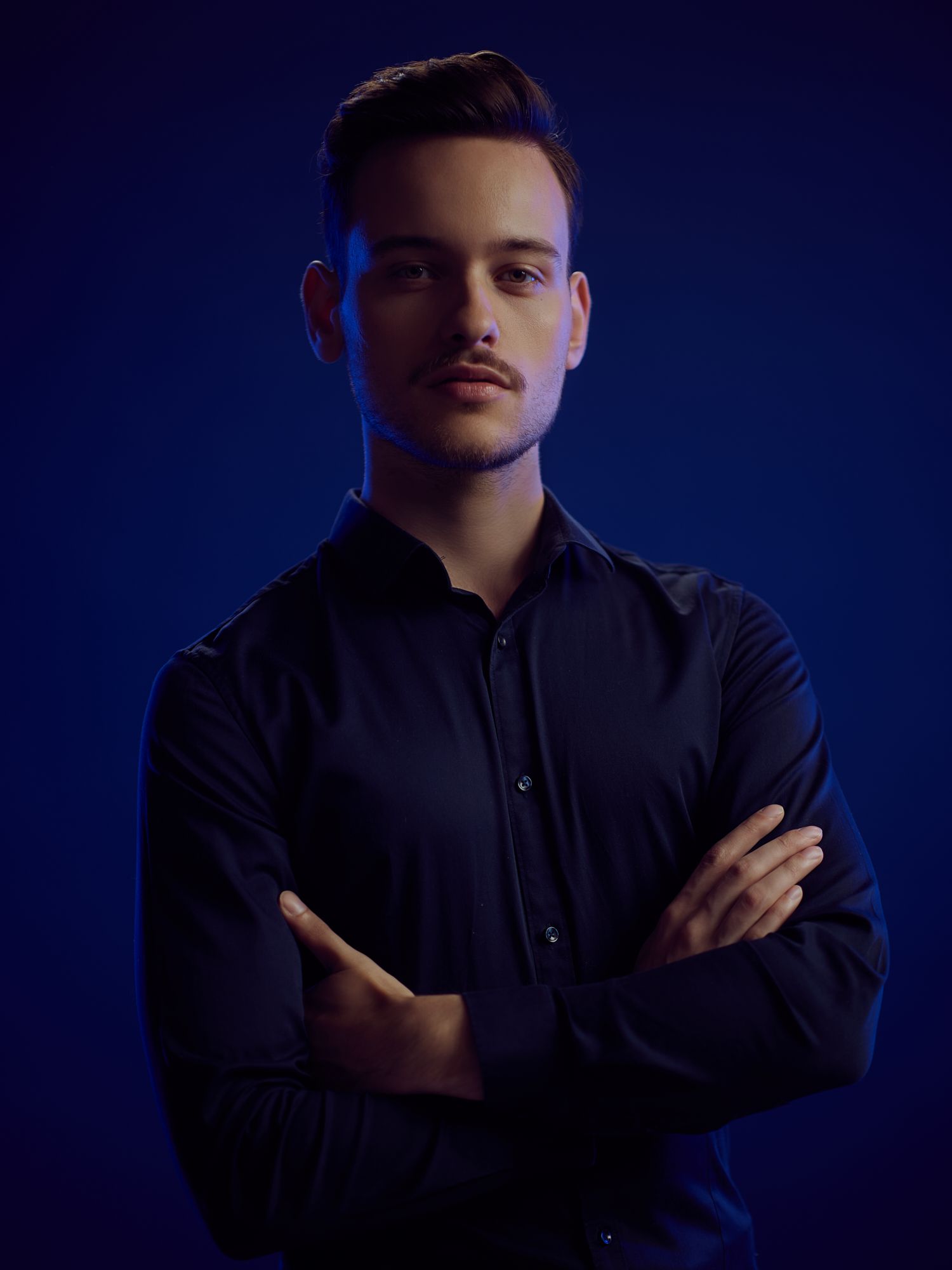 Dramatic portrait series against deep blue background with dark clothing.
