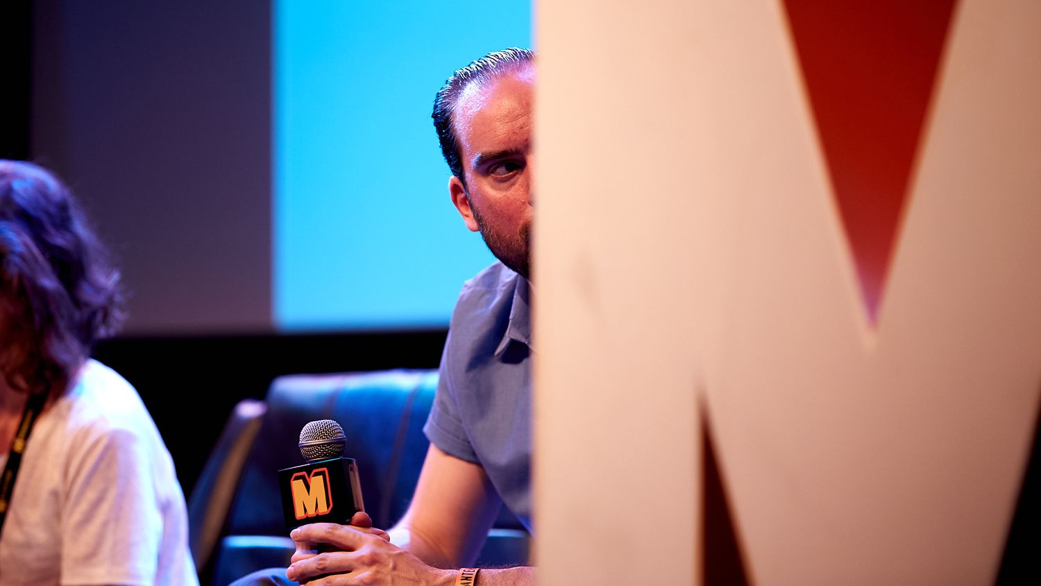Large illuminated TEDx letters glowing against a dark background at an event.
