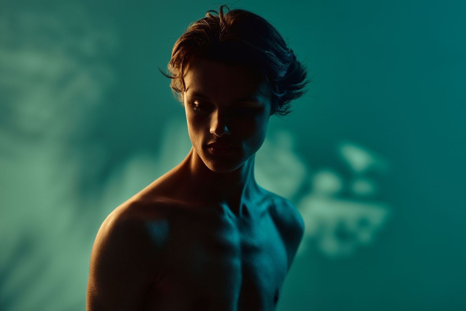 Silhouetted figures in dramatic lighting against a teal background.