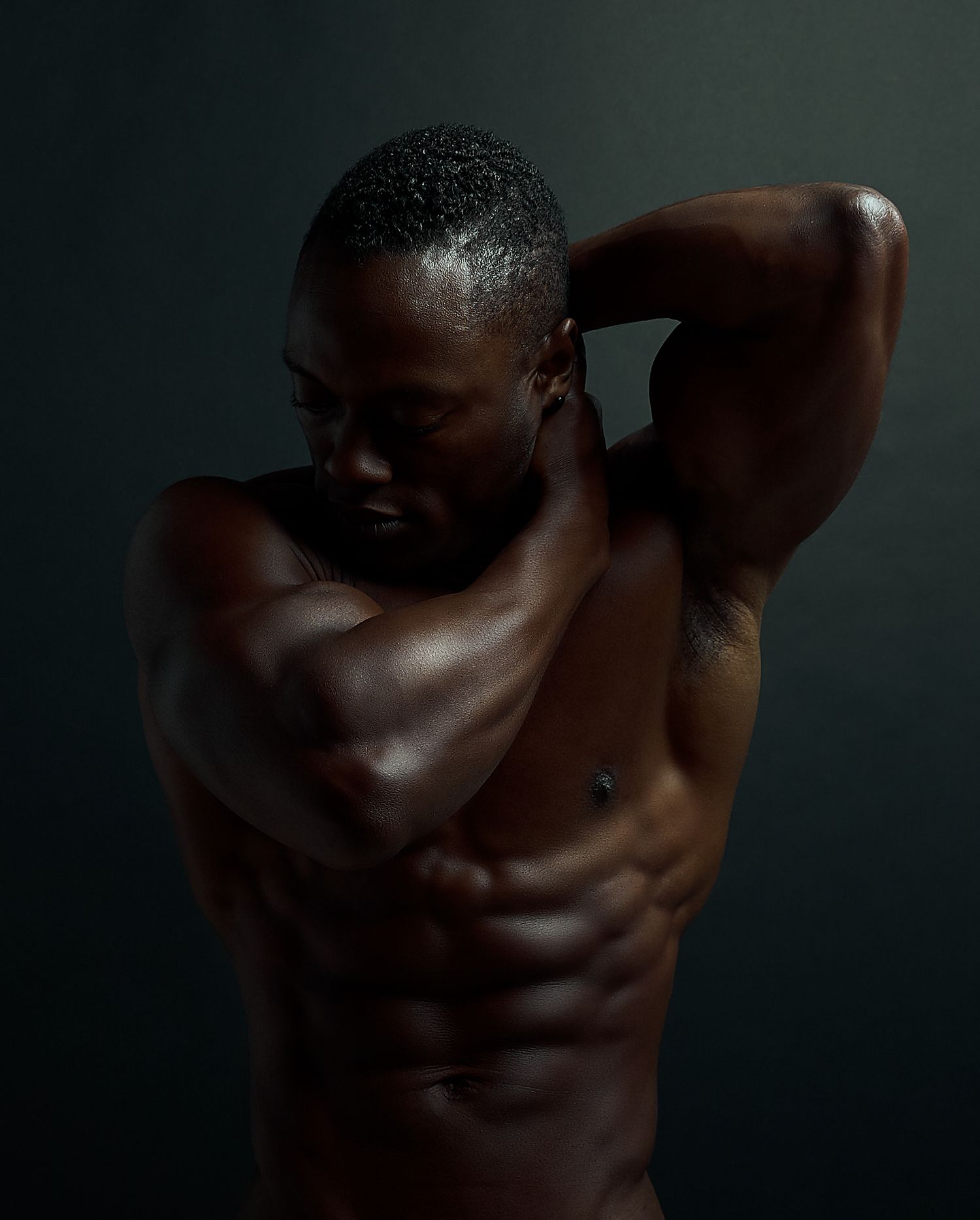 Close-up of sculpted male torso muscles in moody dark lighting.