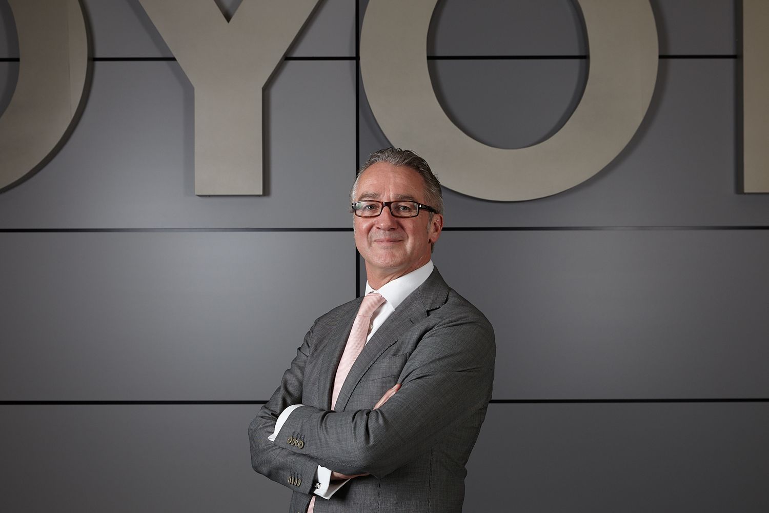 Professional corporate headshots in a modern office setting with gray walls and dramatic lighting.