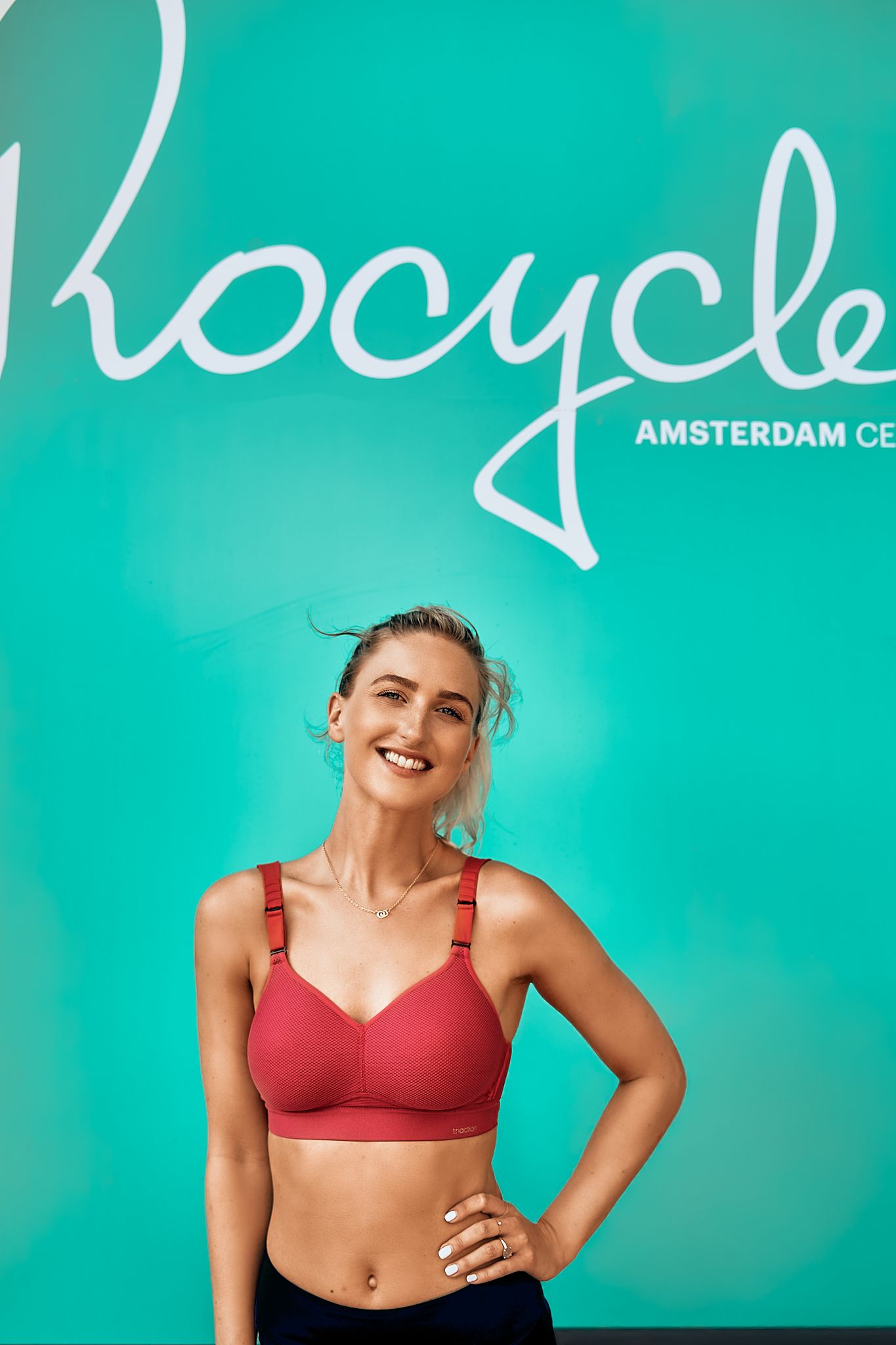 Athletic wear photoshoot against turquoise background featuring red sports bra.