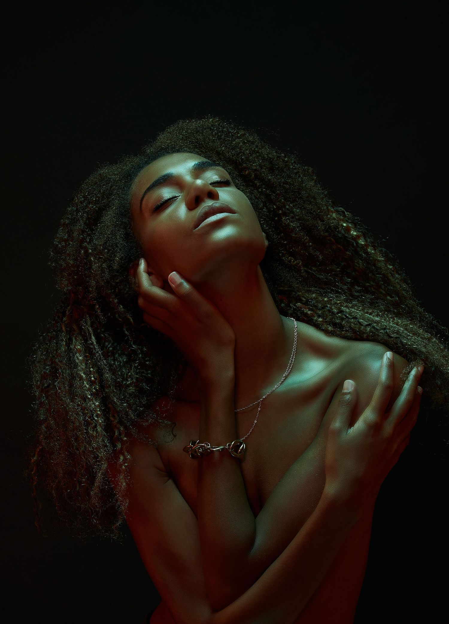Dramatic close-up portrait illuminated with green and red lighting against dark background.