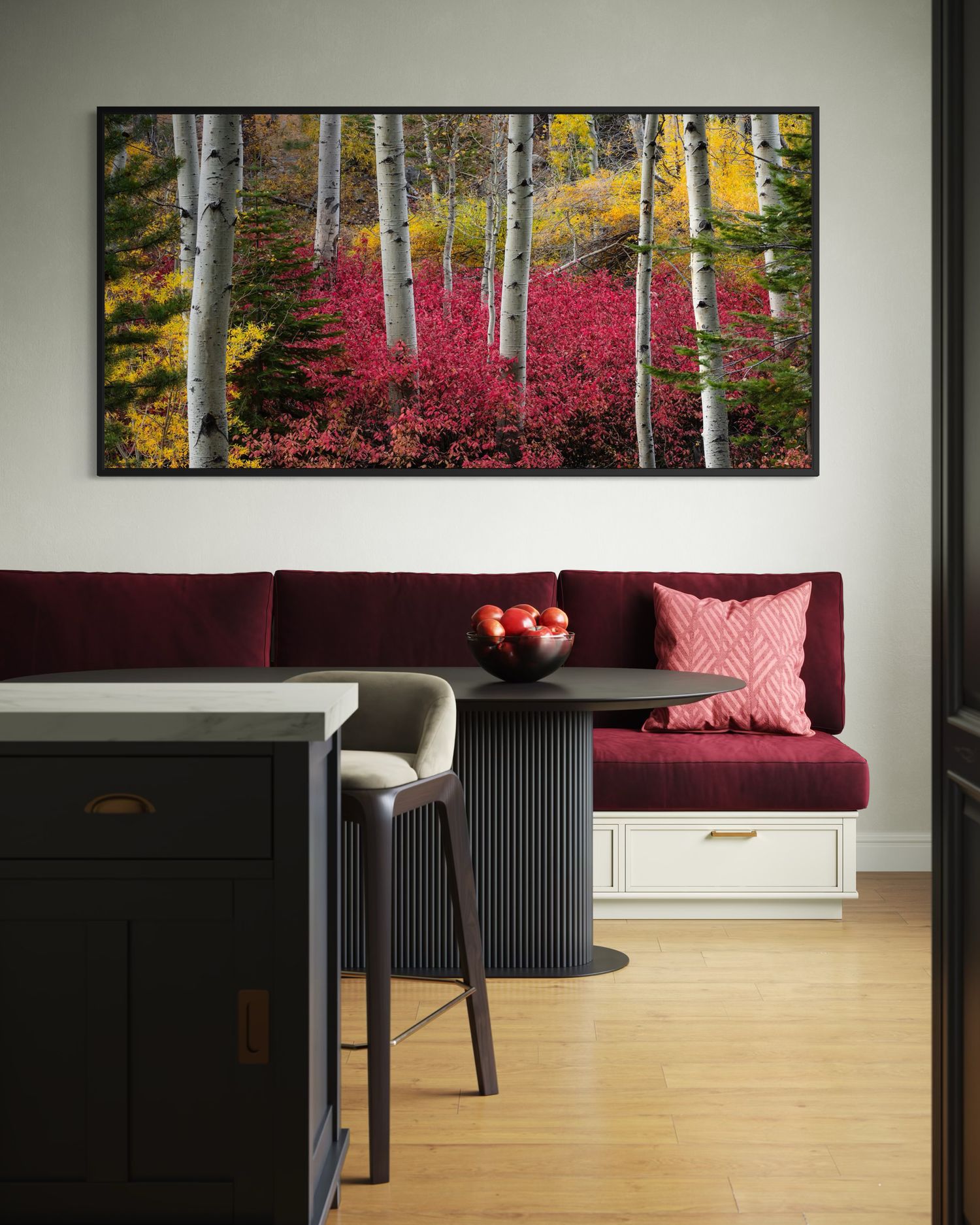 A modern living room features a professional photograph of a panoramic autumn forest landscape and a burgundy sofa against white walls.