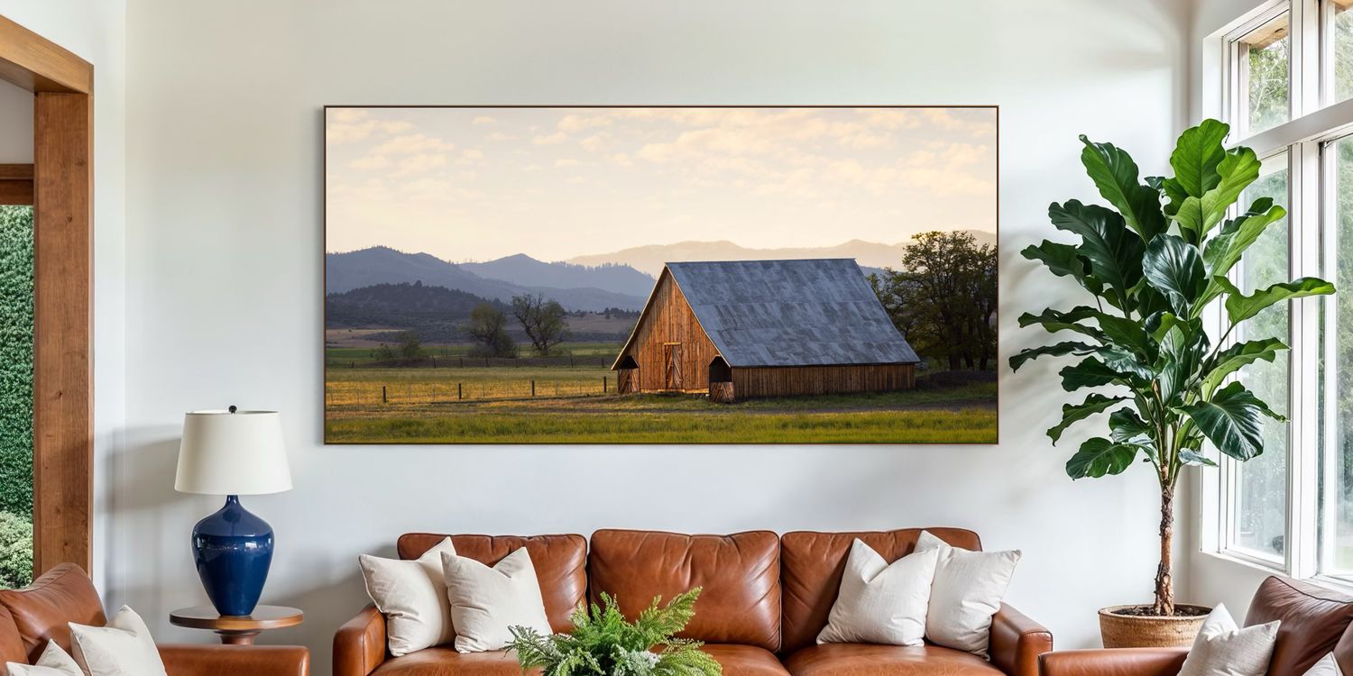 A bright and airy modern living room features a large, framed panoramic rustic barn photograph, large windows, and contemporary furniture.
