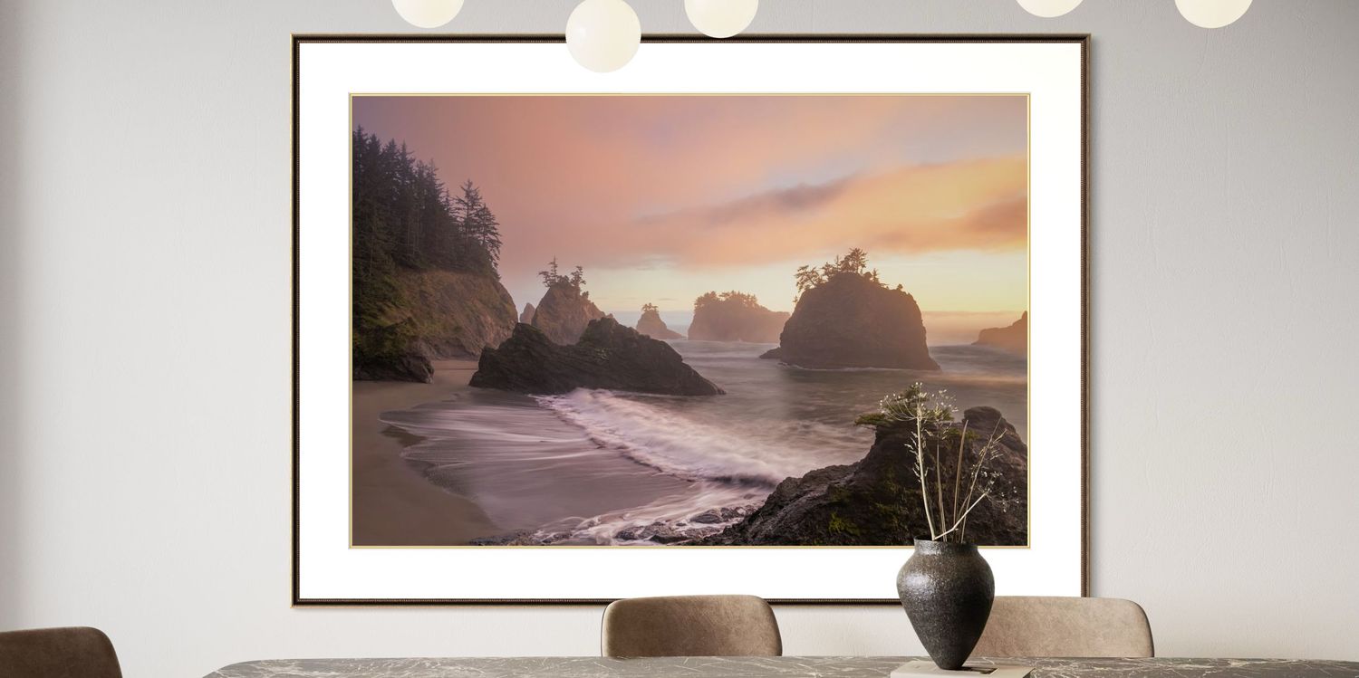 A gallery wall displays a framed landscape photograph of coastal scenes and mountains in a modern interior setting.