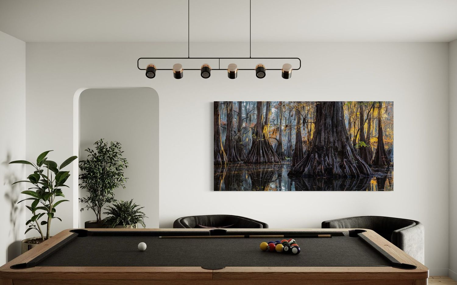 A modern living room interior displays a metal photo print of large cypress trees near track lighting and a wooden pool table.