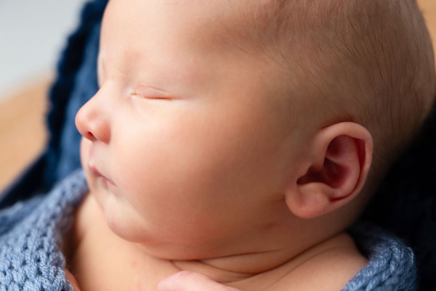 Close-up profile of sleeping newborn baby wrapped in blue knit fabric. Studio photography franklin ky SOKY