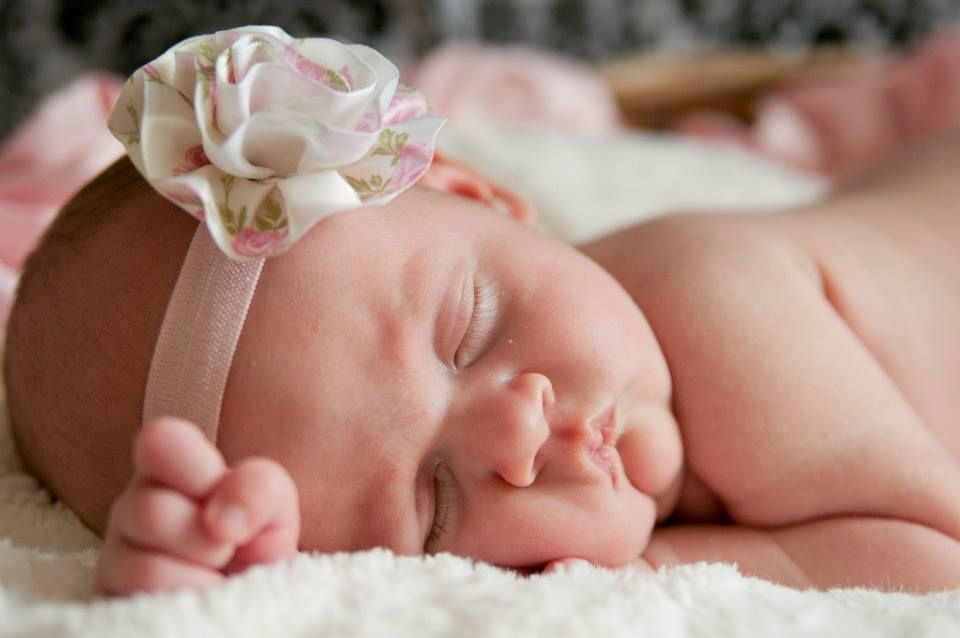 Close up portrait of sleeping newborn baby on white textured blanket.
