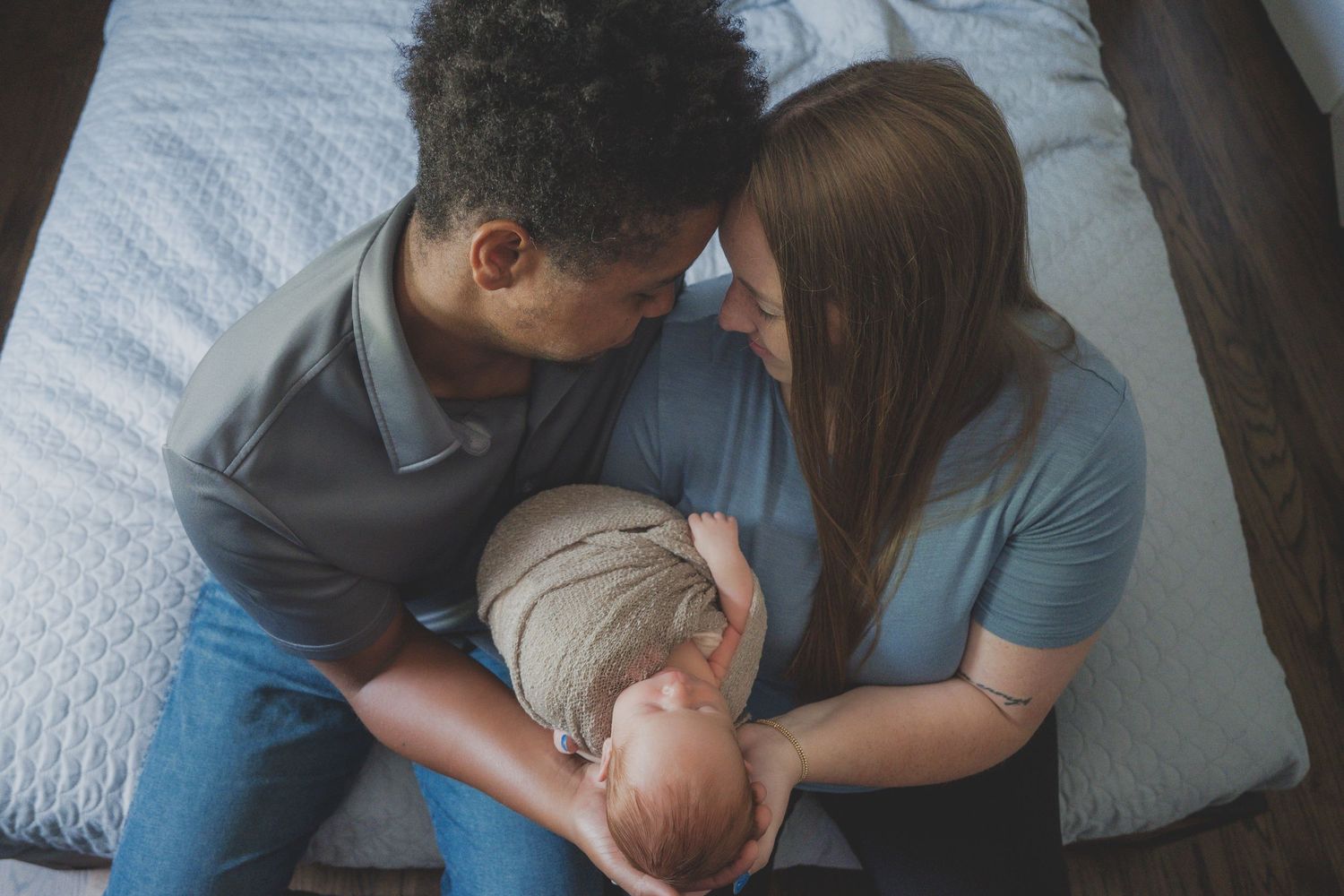Family sitting together on gray couch for intimate photo session.