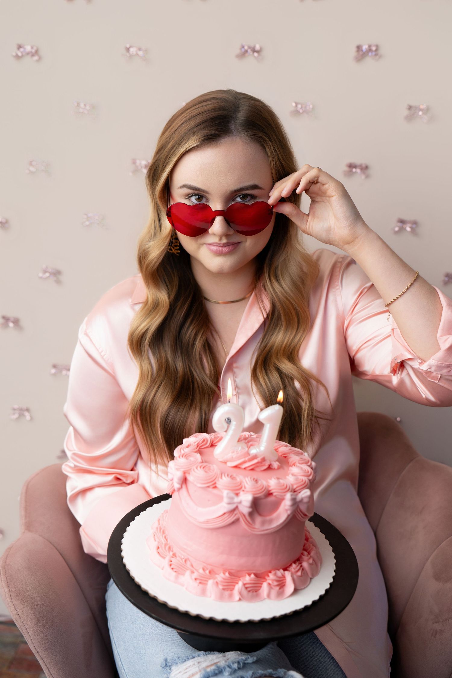 A series of photos showing someone in a pink sweater posing with and eating a pink frosted cake.