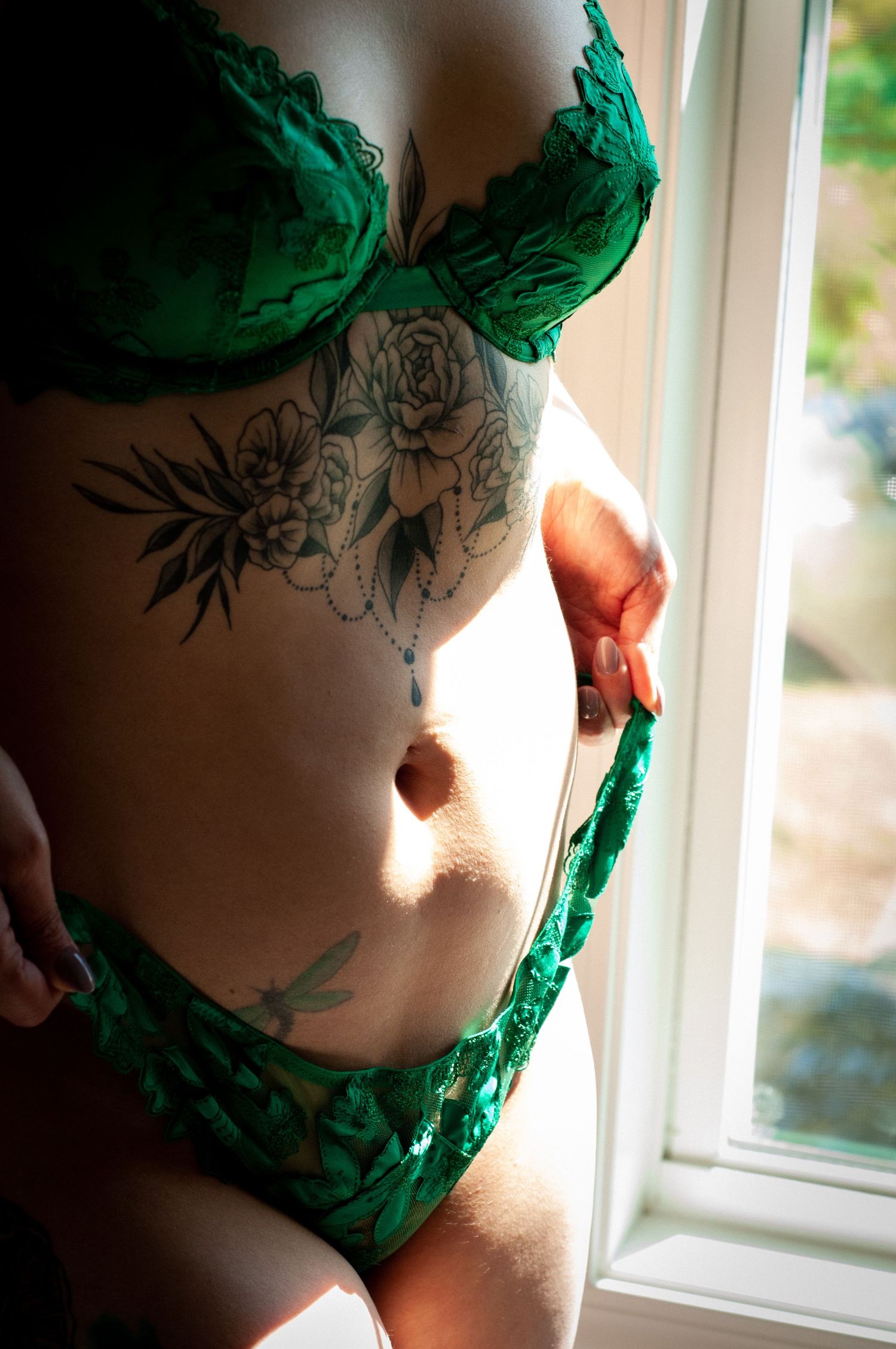 Intimate boudoir photography featuring emerald green lingerie and floral tattoo details.