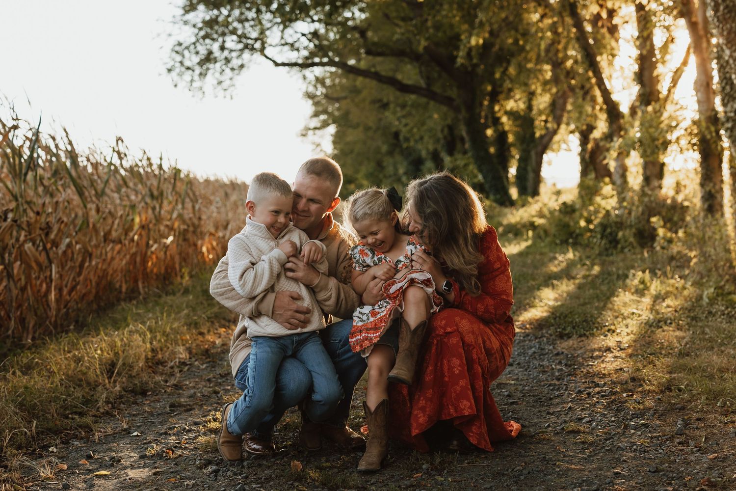 Family enjoying a golden sunset together on a rustic path through tall grass and autumn foliage.